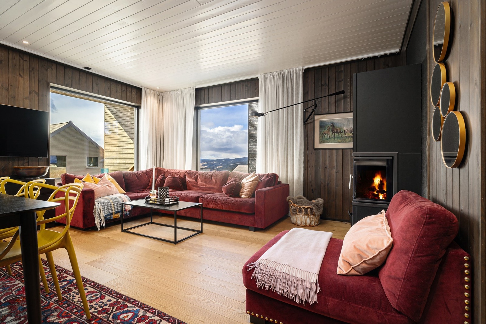 Innbydende stue med peis og store vindusflater som slipper naturen inn. Galleribilde