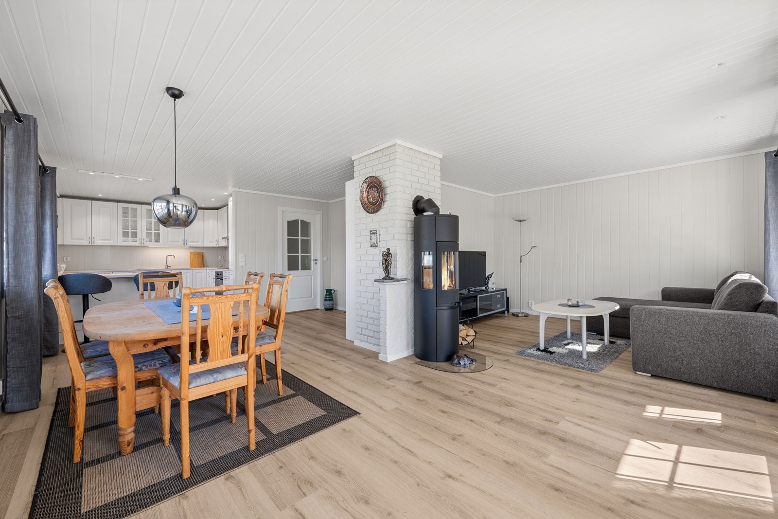 Stuen og kjøkkenet danner et stort allrom med plass til både spisebord og sofagruppe. Gjennomgående laminatgulv og lyse, malte panelvegger. Galleribilde