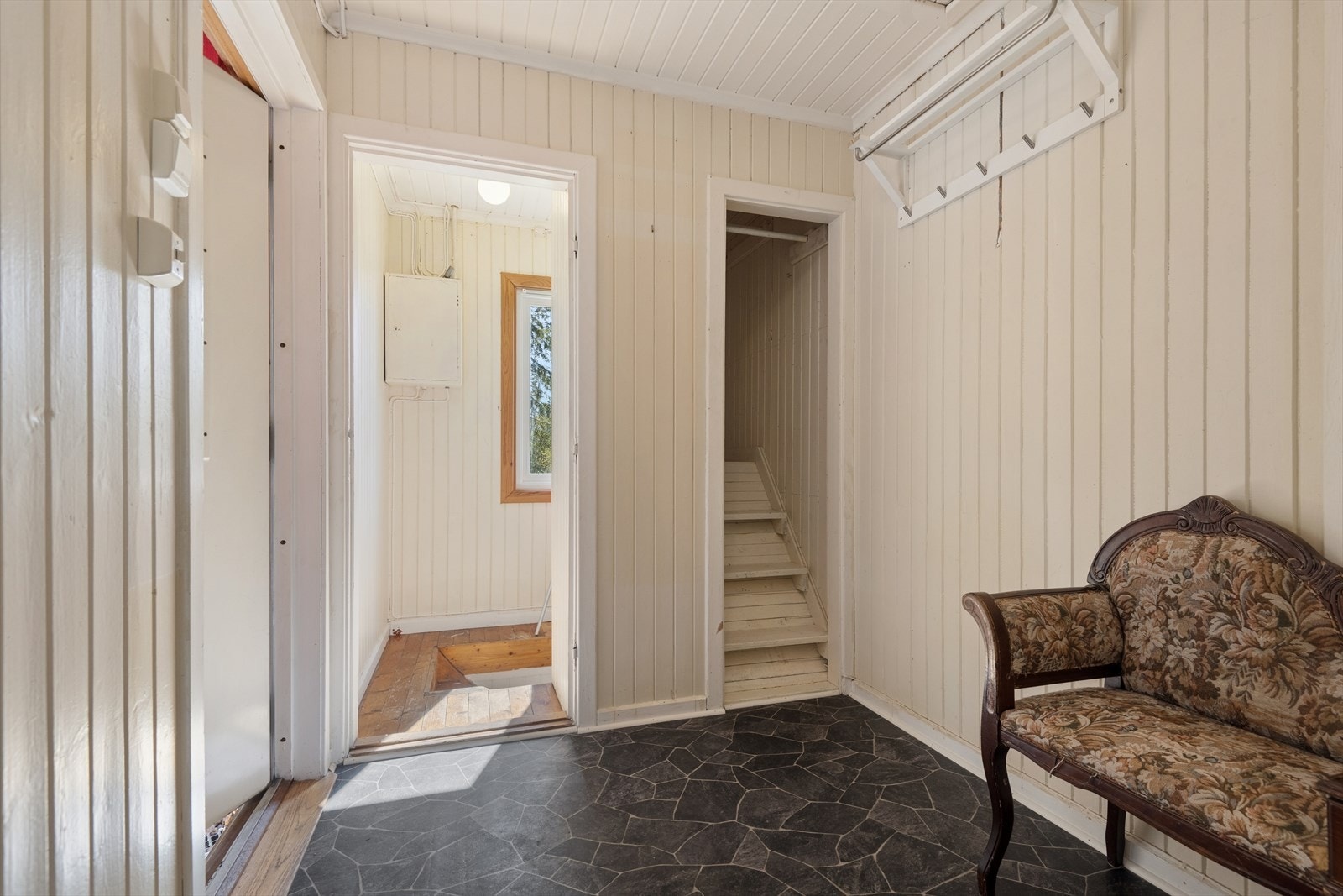 Entréen har malte panelvegger og trapp ned til kjelleretasjen. Galleribilde