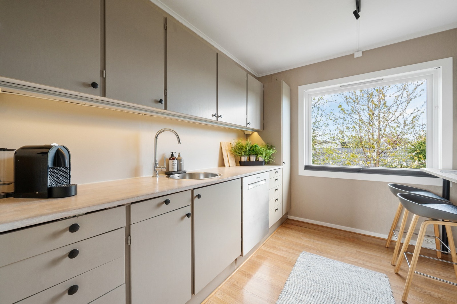 Kjøkkenet er utstyrt med både komfyr og oppvaskmaskin. En diskré ventilator er plassert i overskapet for å bevare det ryddige uttrykket i rommet. Galleribilde