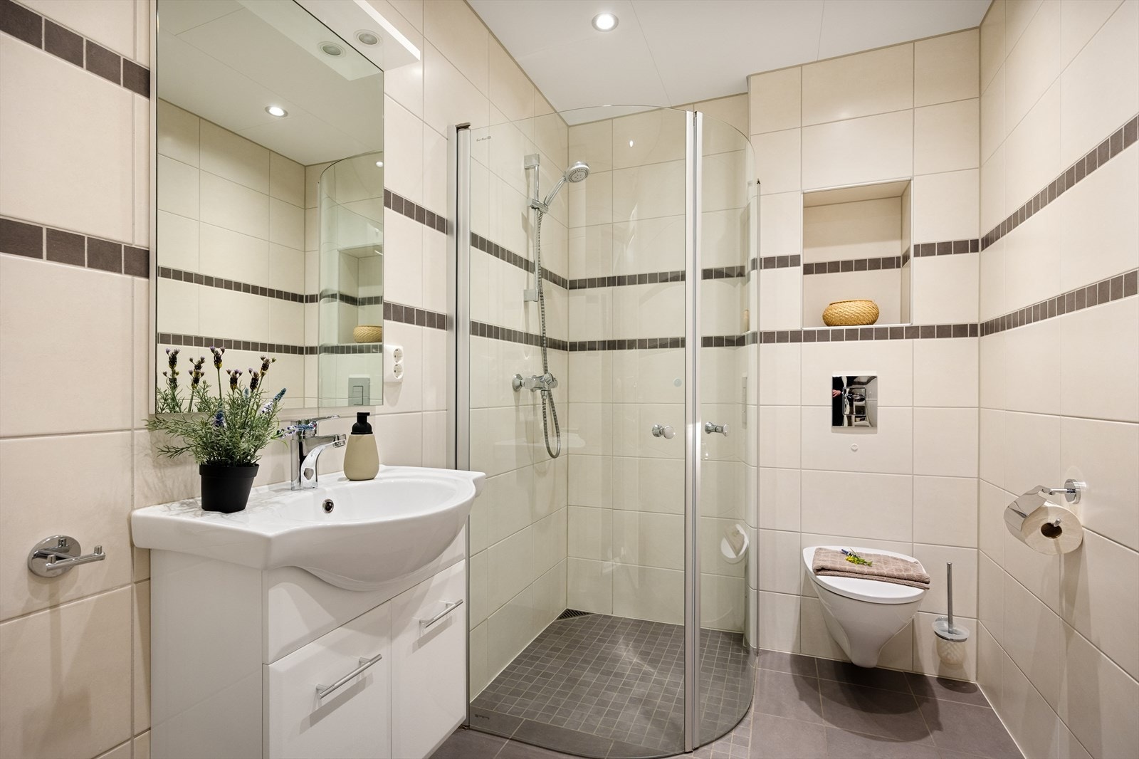 Badet i underetasjen er også helfliset og innredet med dusj med glassdører, veggtoalett og baderomssinnredning. Galleribilde