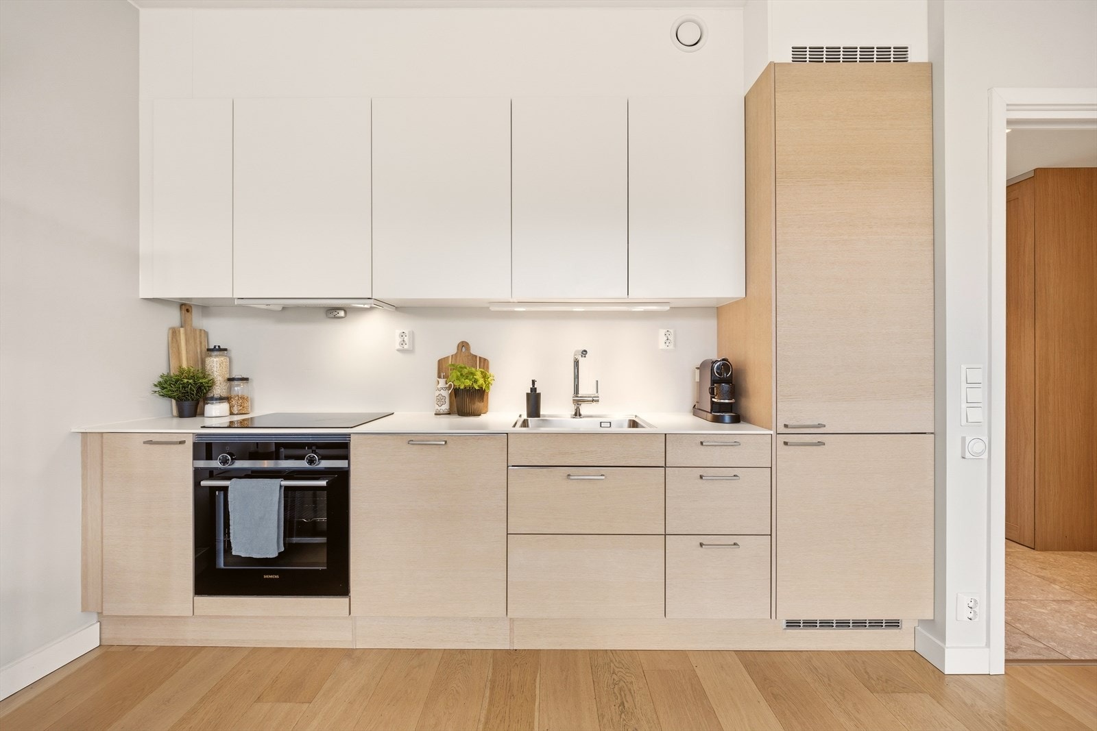 Kjøkkenet er minimalistisk med et stilrent, skandinavisk design og integrerte hvitevarer for et ryddig uttrykk. Galleribilde