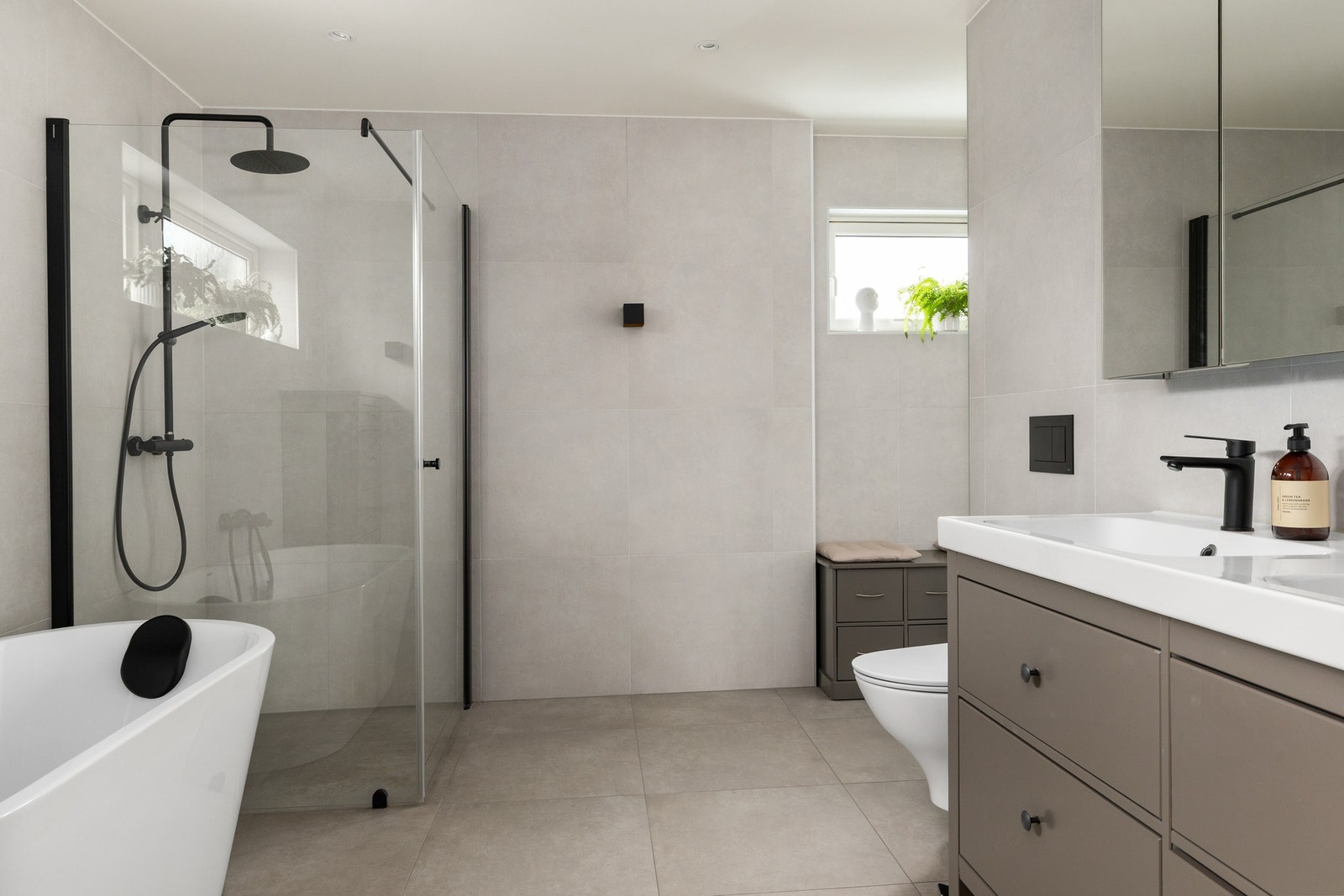 Badet er flislagt i store moderne fliser og har lune og moderne farge- og materialvalg. Dusj og badekar gir både spafølelse og en praktisk hverdag for småbarnsfamilien! Galleribilde