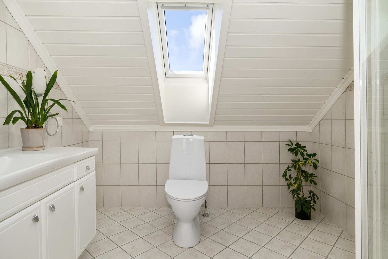 Lyst flislagt bad på loft. Badet har vegghengt innredning og elektriske varmekabler i gulv Galleribilde