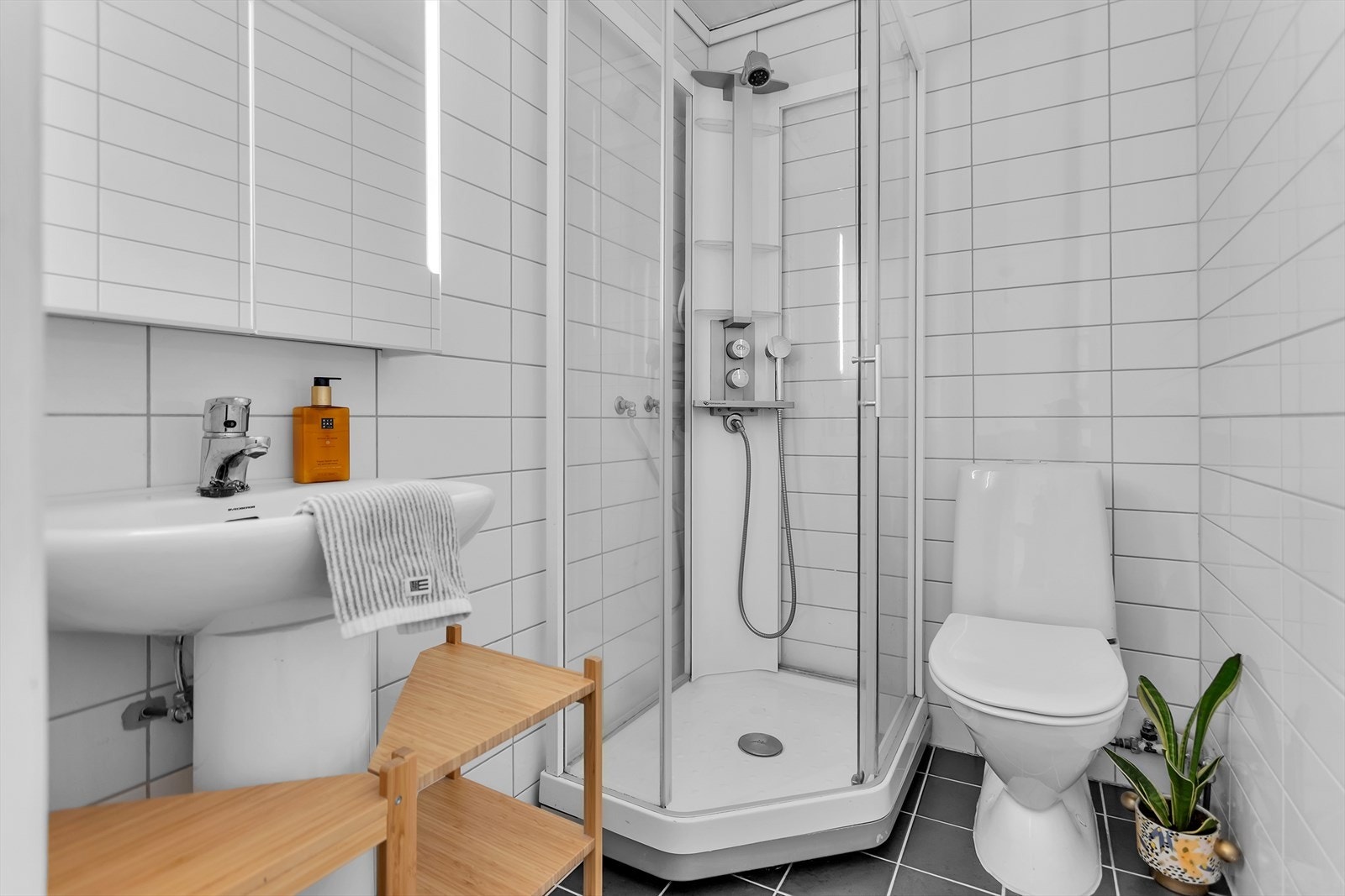 Moderne og stilrent helfliset baderom fra 2014 som kombinerer funksjonalitet og estetikk. Badet er utstyrt med et praktisk dusjkabinett, speilskap med integrert belysning, servant og toalett. Det er varmekabler i gulvet. Galleribilde