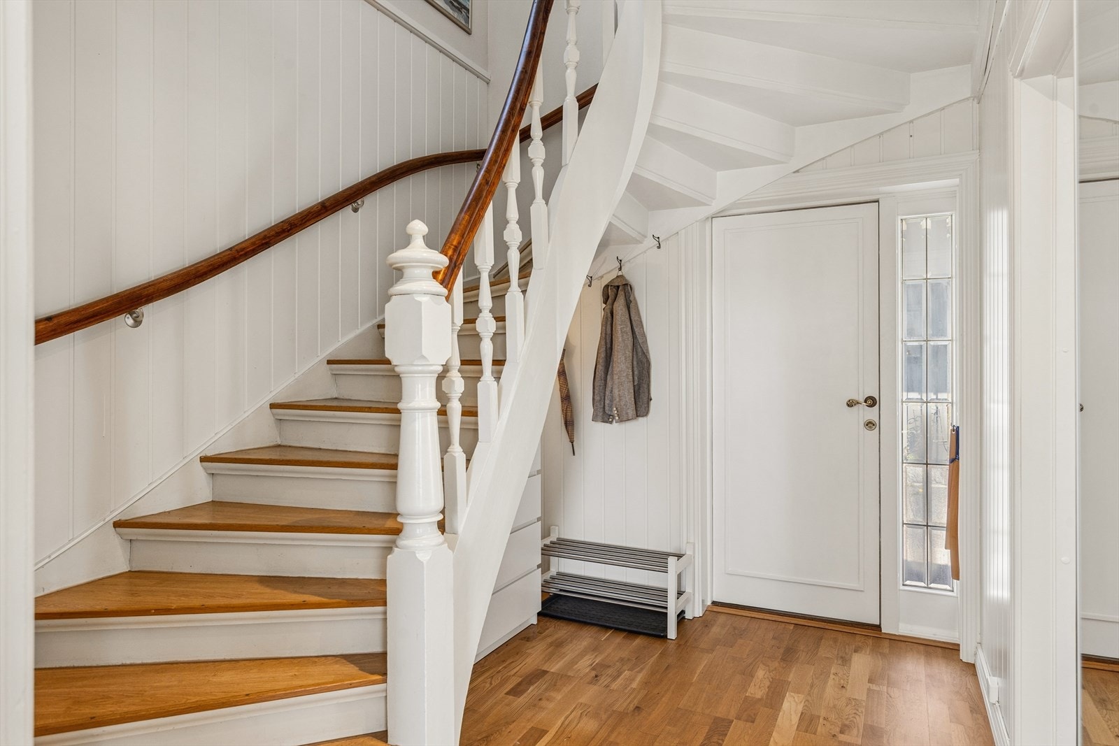 Entréen ønsker velkommen med 3-stavs parkett på gulvet og en malt tretrapp som leder opp til andre etasje. Galleribilde