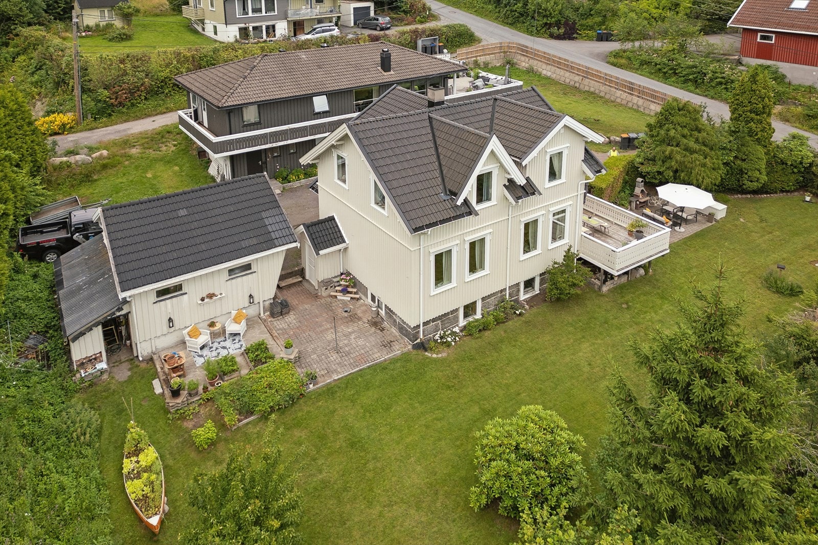 Oversikt over eiendommen som viser boligen, garasjen og den store hagen. Galleribilde