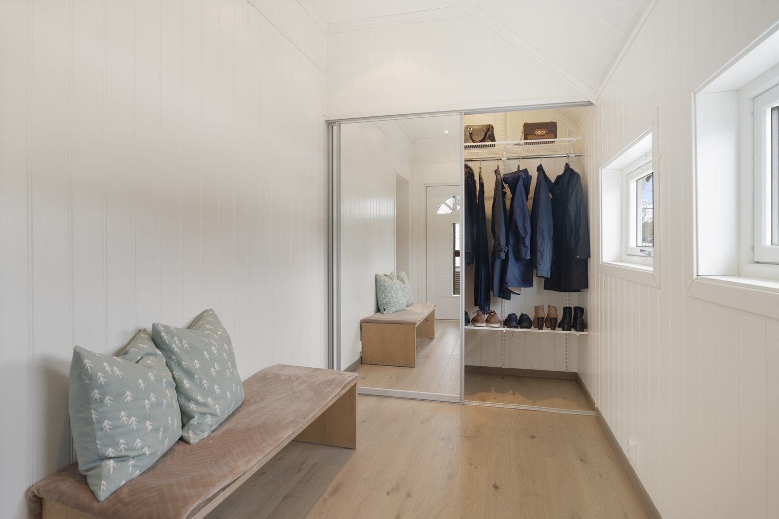 Et lyst og meget romslig vindfang ønsker deg velkommen inn i boligen - her er det masse oppbevaringsplass i stor skyvedørsgarderobe Galleribilde
