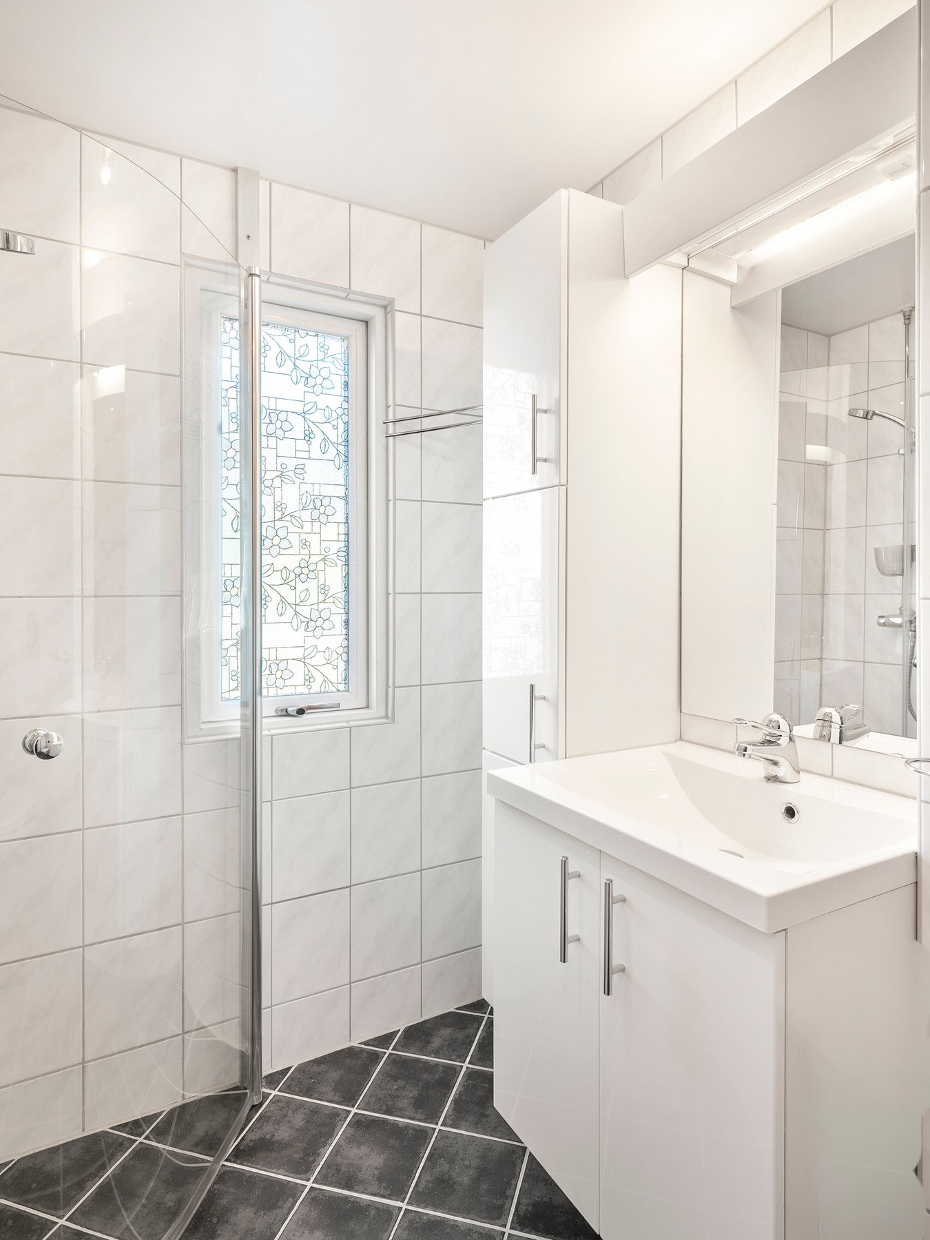Badet er utstyrt med sanitærutstyr, herunder veggmontert toalett, dusjnisje, servant og opplegg for vaskemaskin. Galleribilde