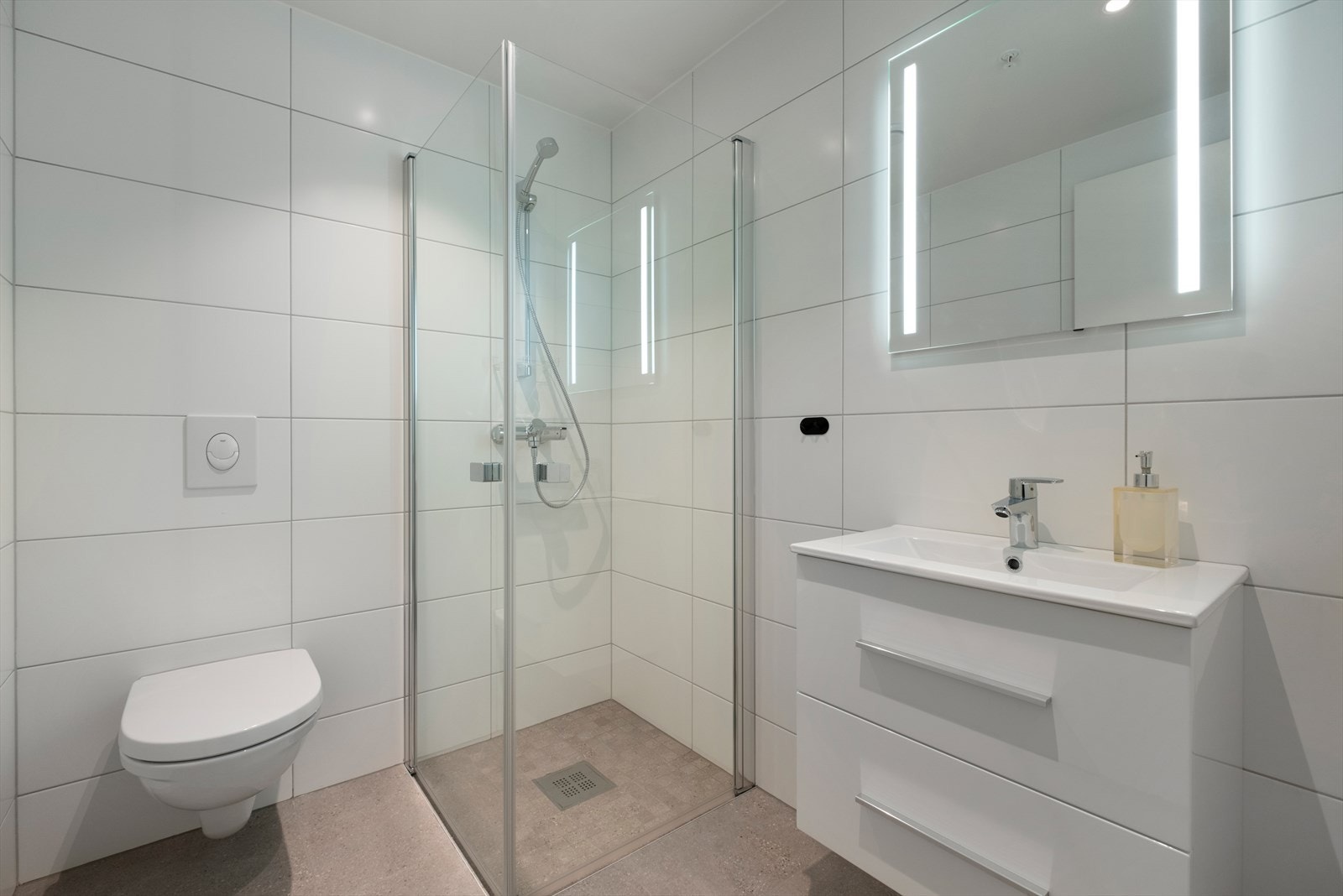 Bad 2 har flott innredning, vegghengt WC og 60x60-flis på gulv med mosaikk og fall i dusjsone. Galleribilde