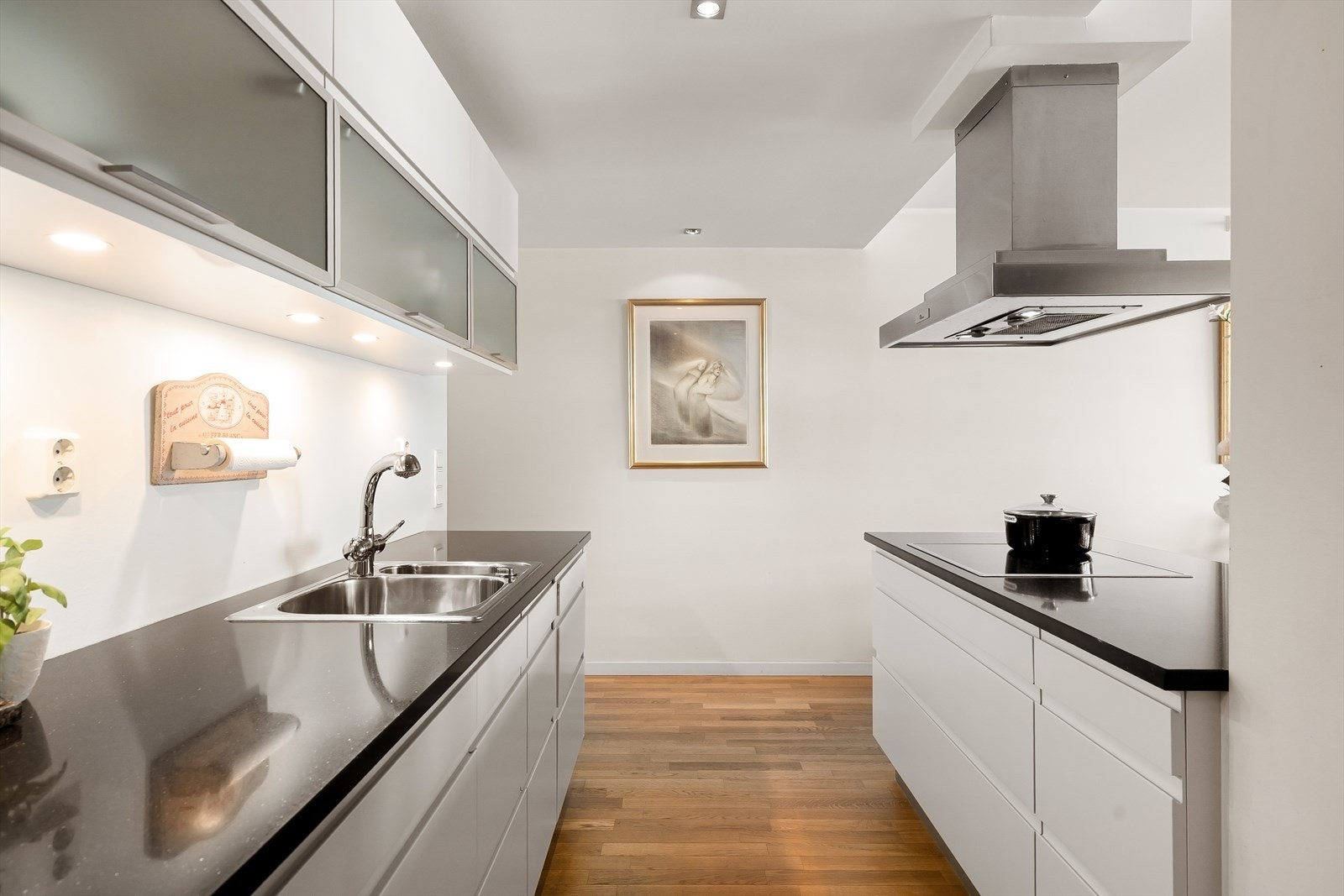Moderne HTH kjøkkeninnredning med glatte, hvite fronter. Polert naturstein benkeplate. Galleribilde