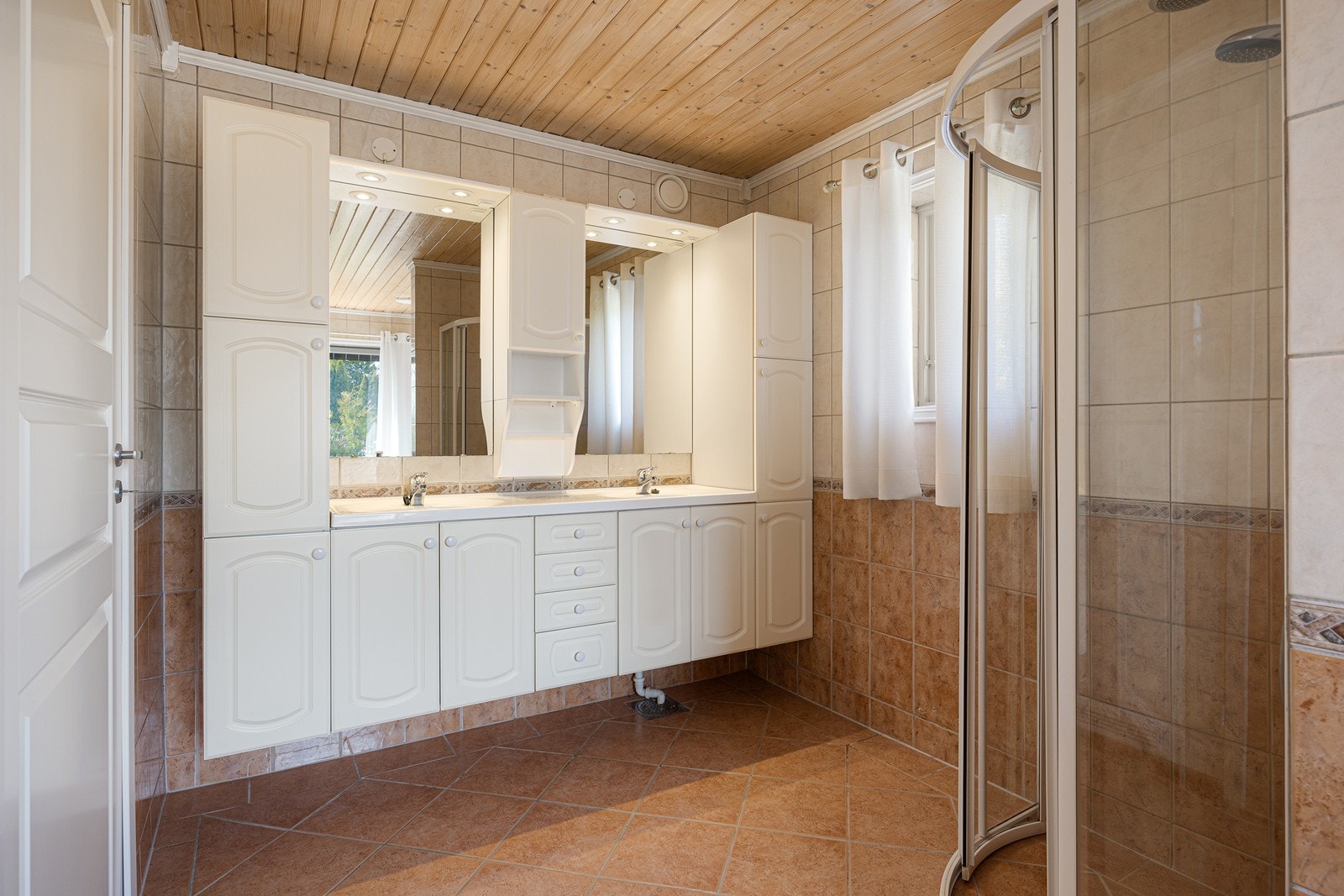 Badet er helfliset og varme er lagt i gulvet. Dusjhjørnet er innredet med regnfallsdusj og skyvedør av glass. Galleribilde