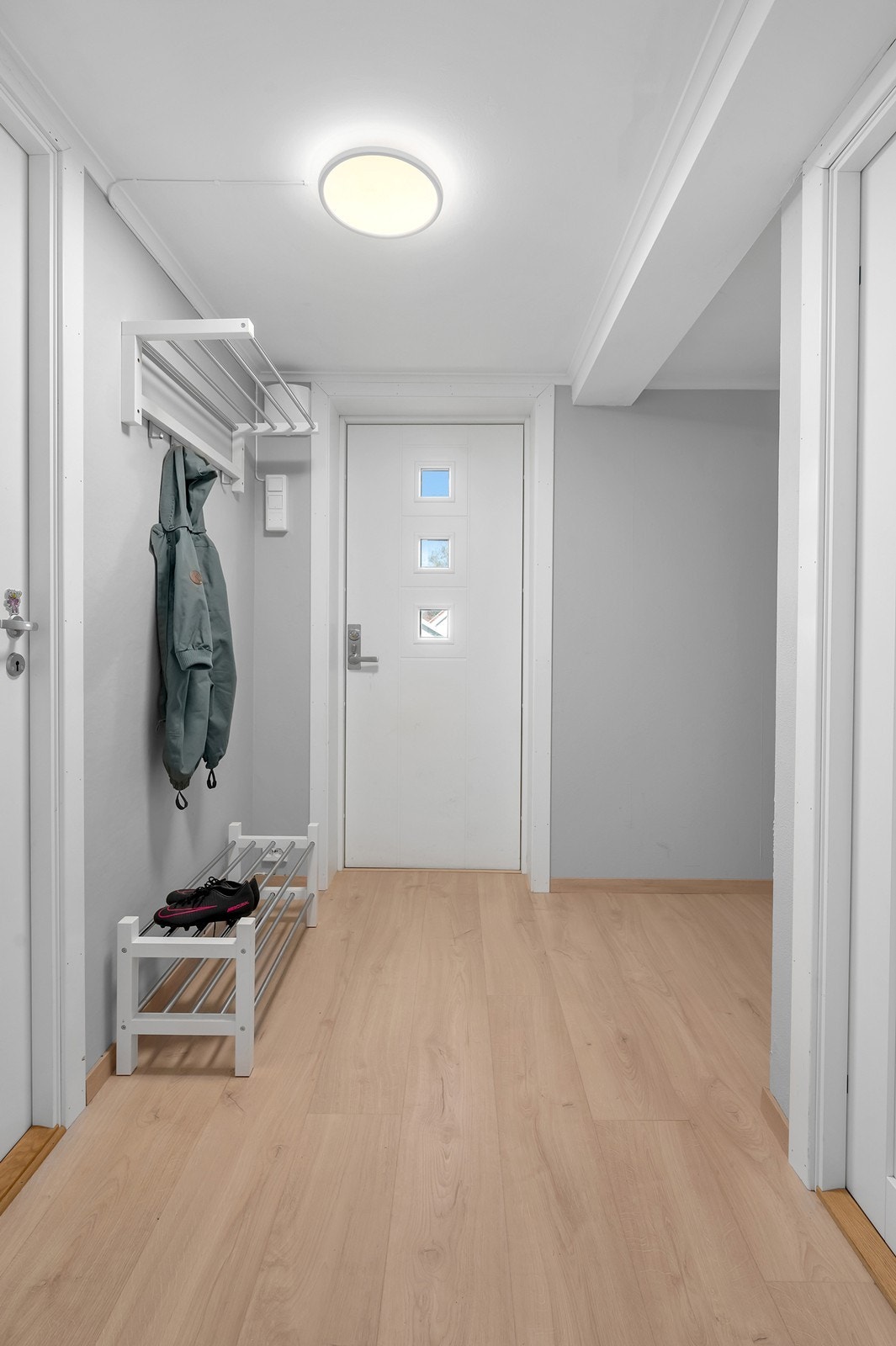 Velkommen inn i en grei gang med plass til ytterklær og sko. Pen inngangsdør. Galleribilde