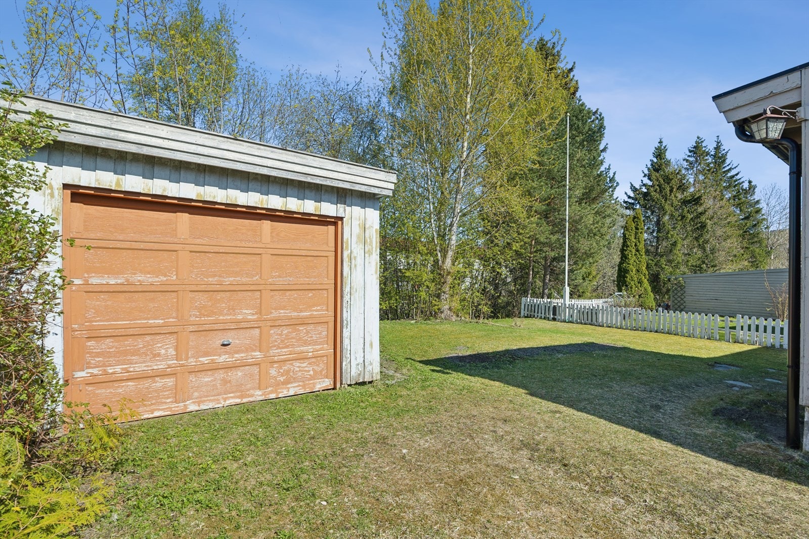 På motsatt side finnes et romslig plenareal som grenser til skog. Her er det også oppført en frittstående garasje. Galleribilde