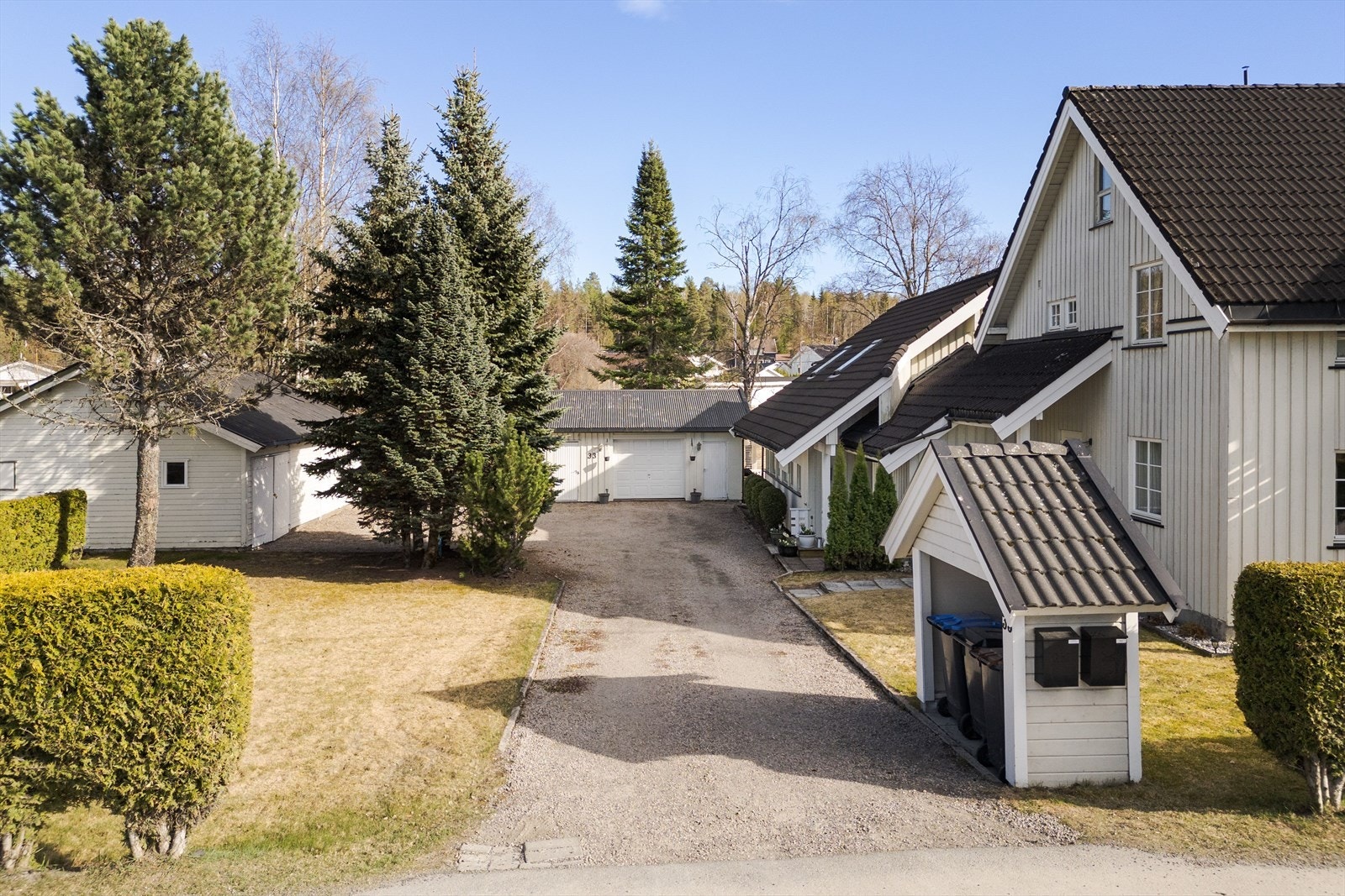 Gruset innkjøring og gårdsplass. Søppelhus med postkasser. Galleribilde