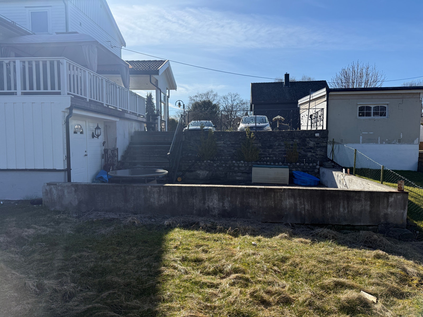 Uteområdet med stor terrasse rett ved plenen, her er også inngangsdøren Galleribilde