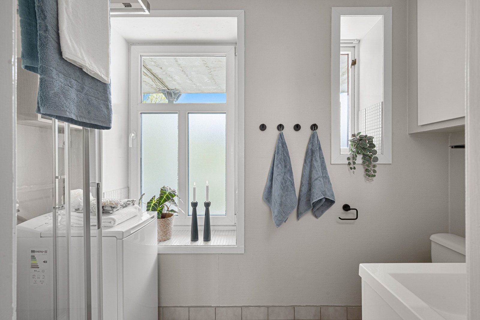 Badet har opplegg for vaskemaskin, dusjkabinett, toalett og servant. Dette vender ut mot den disponible uteplassen tilhørende leiligheten. Våtrommet er av eldre og ukjent dato, og renovering anbefales ifølge takstmann. Galleribilde