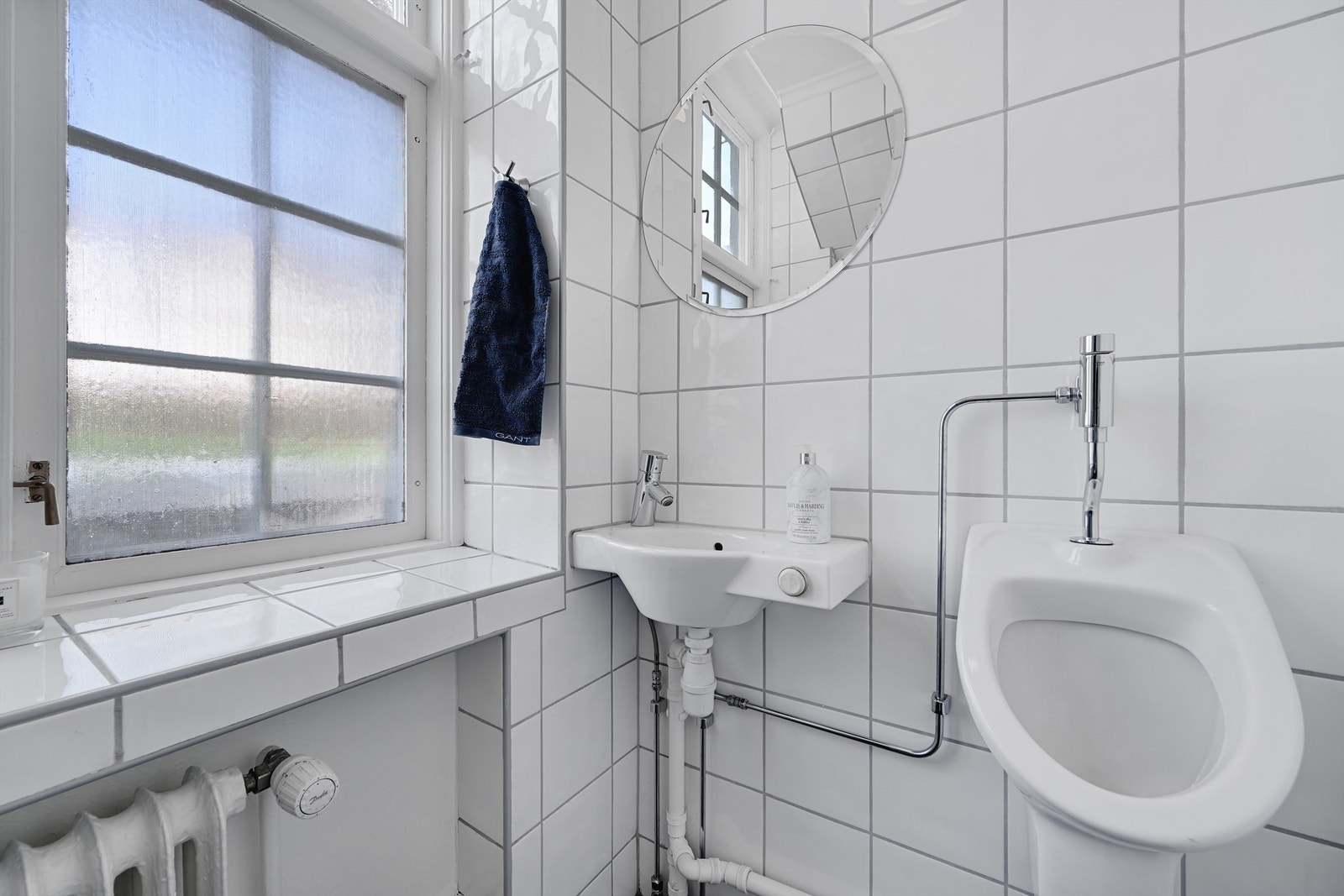 Praktisk toalettrom i første etasje med flislagte vegger, håndvask og urinal. Galleribilde