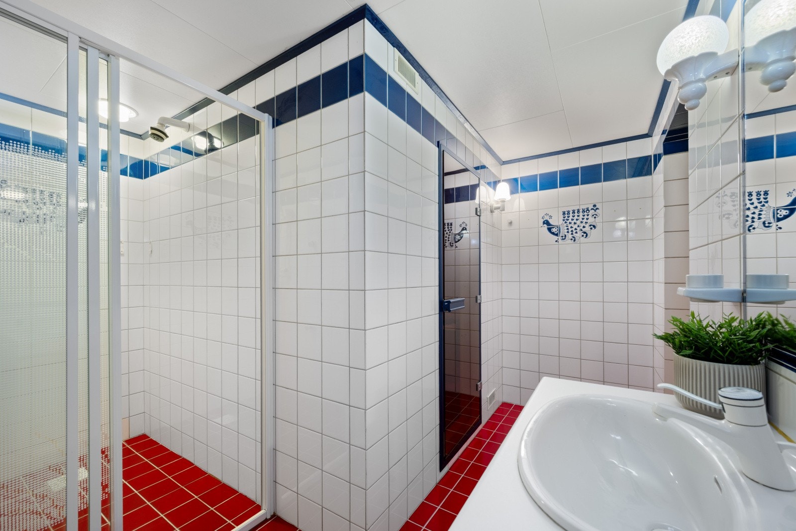 Badet i kjelleren har flislagte overflater, en profilert innredning med servant og ett-greps blandebatteri, gulvmontert toalett og en dusjnisje med skyvedører i glass. Galleribilde