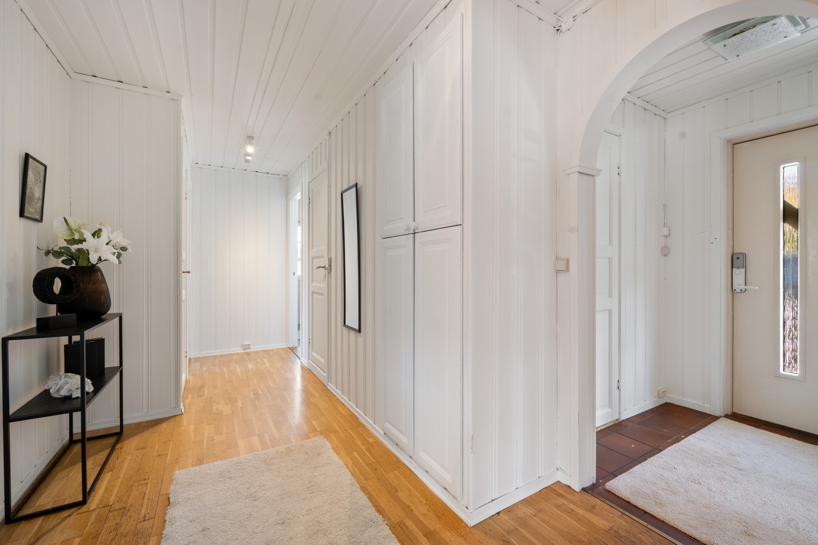 Vindfang med fliser på gulvet og lysmalt panel på veggene, som gir et hyggelig og innbydende førsteinntrykk. Galleribilde