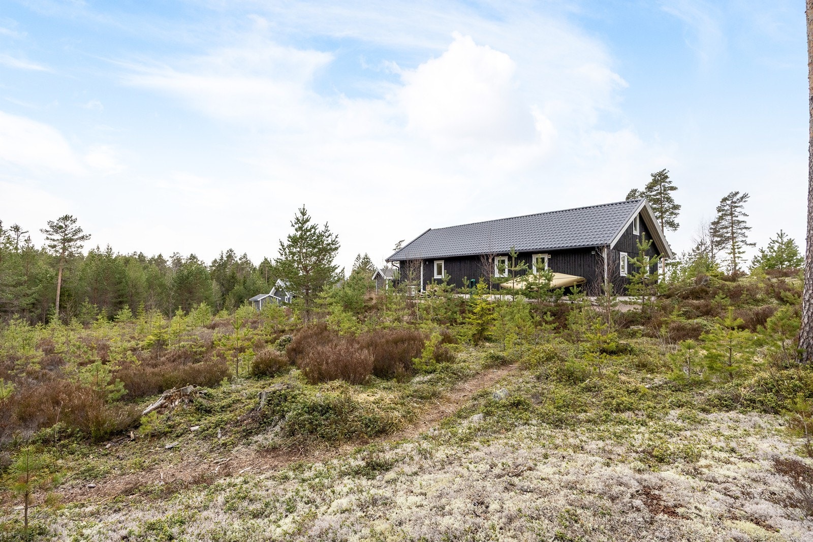 Tomten er over to mål, der en gruslagt gårdsplass suppleres av lyng, trær, gress og annen stedlig vegetasjon. Galleribilde