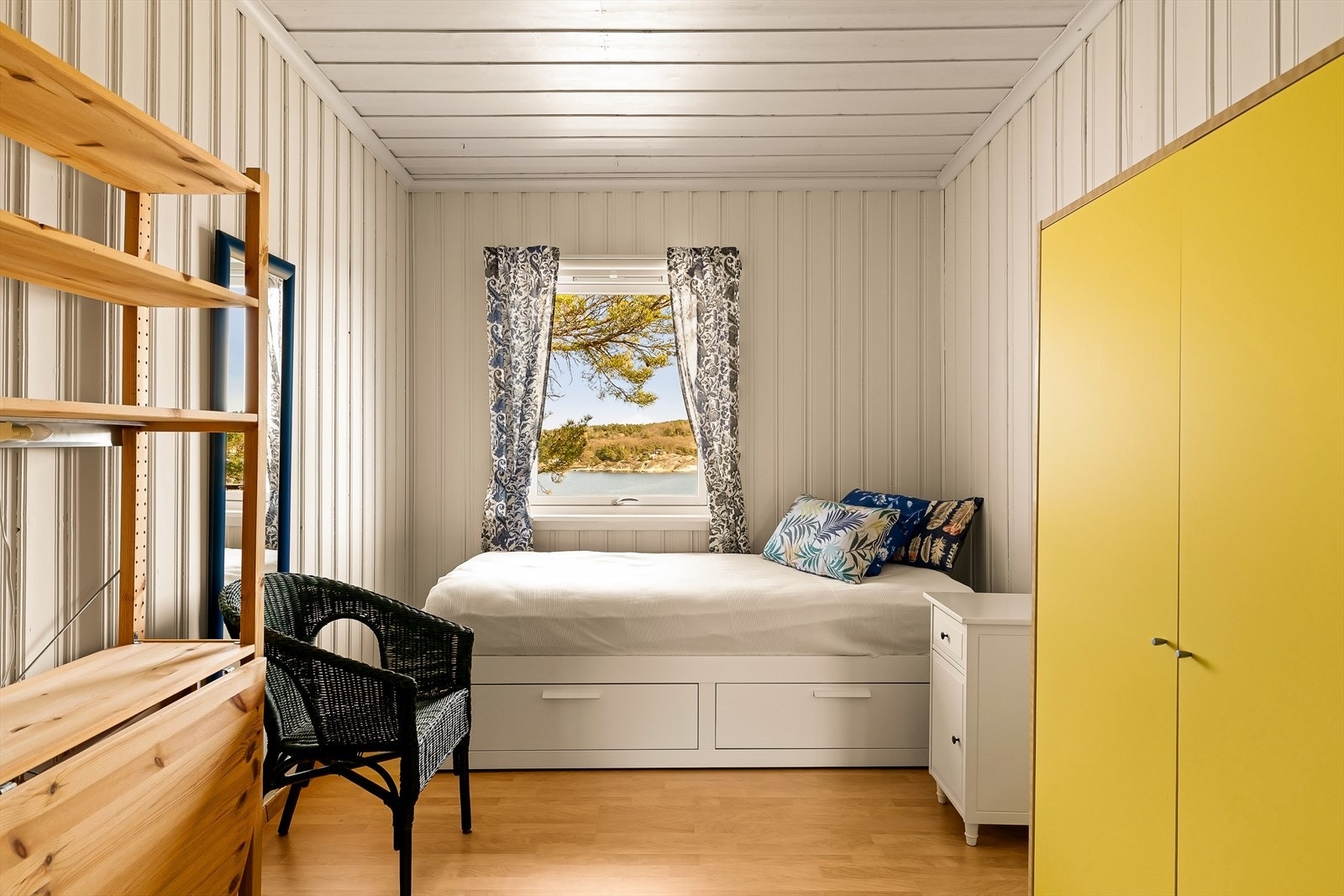 Et lyst og trivelig soverom med klassisk trepanel på vegger og i tak. Galleribilde