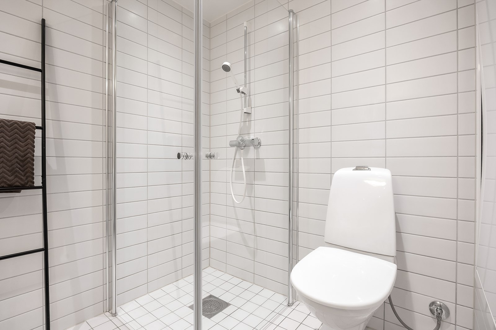 Badet er utstyrt med servantinnredning, dusjhjørne med innfellbare glassdører og vegghengt toalett. Galleribilde