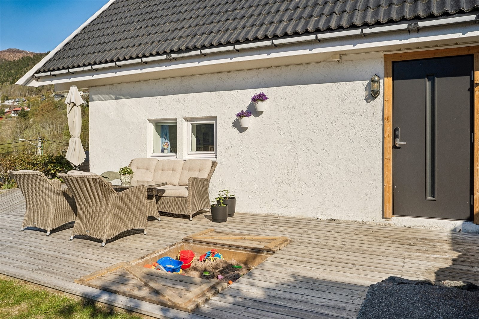 Fleire supre terrassar, og uteplassar rundt omkring på tomta og ved husvære. Her er rett ved det som i dag vert nytta som hovudinngang. Godt med terrasseplass, og nedfelt sandkasse - med lokk (terrassebord) sjølvsagt! Galleribilde