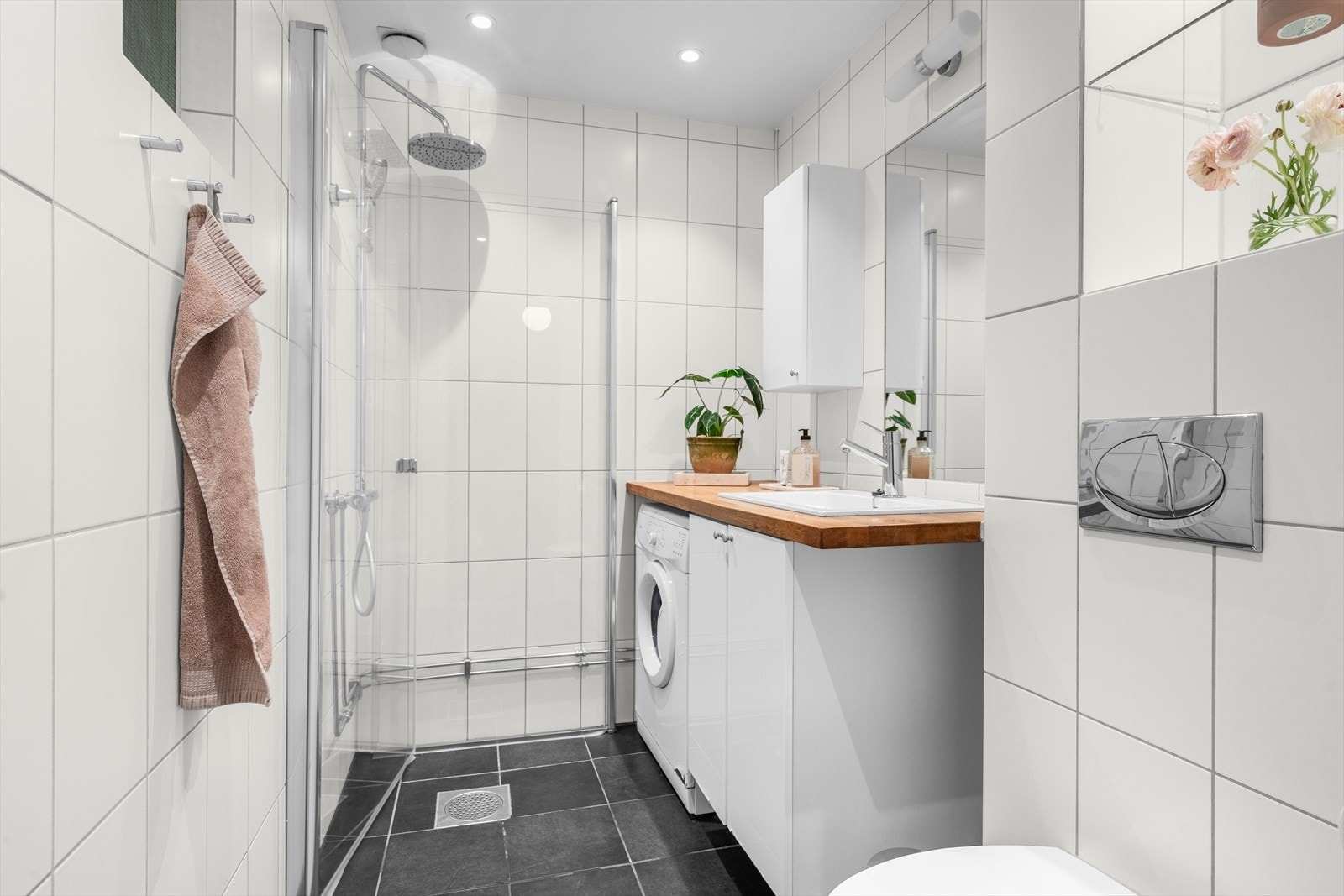 Pent flislagt bad renovert i 2007 med dusjhjørne (nye glassdører i 2026), opplegg for vaskemaskin, servant og veggskap. Galleribilde