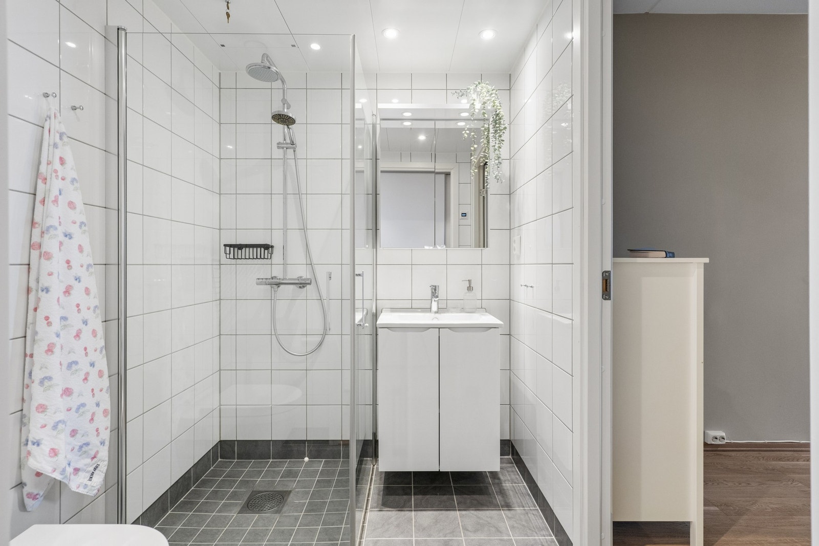 Bad 2 er et delikat og flislagt baderom med dusjhjørne, servant i innredning og downlights i himling. Galleribilde