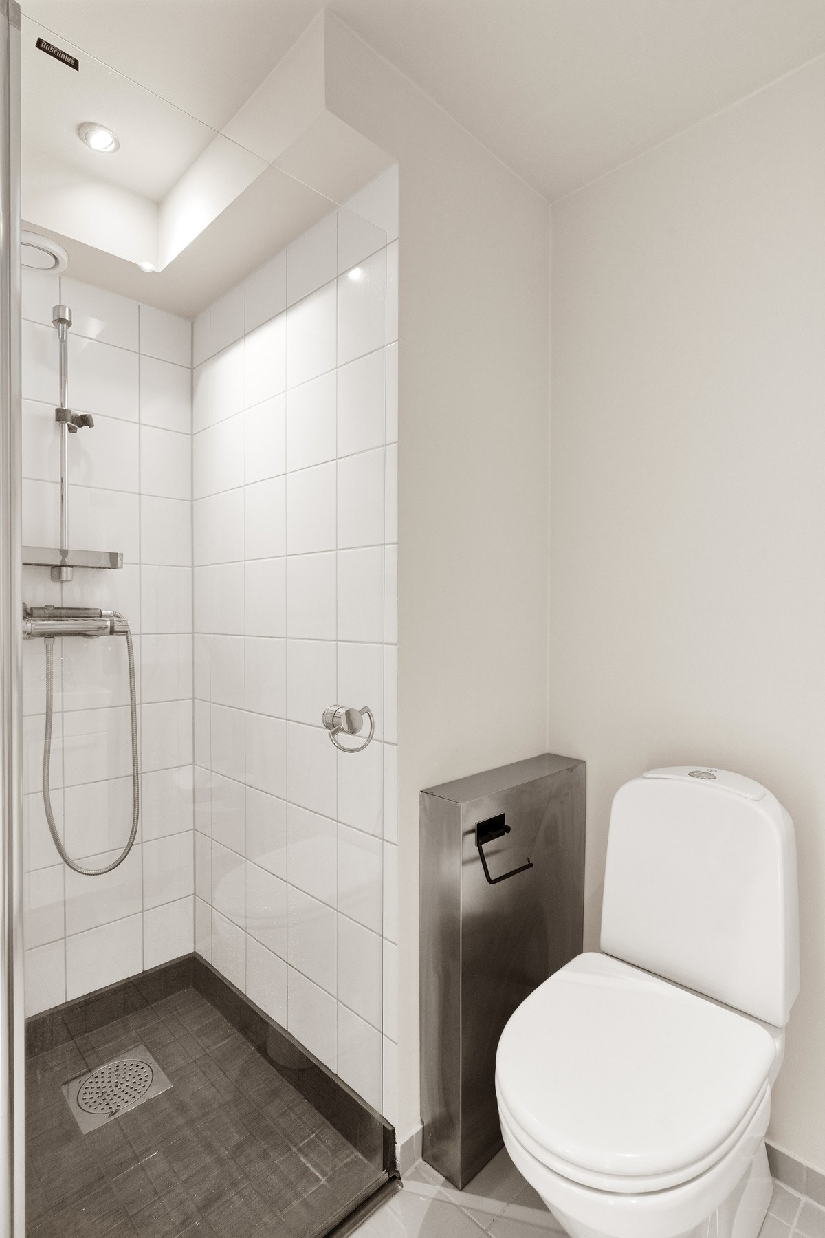 Enkelt, pent baderom med wc, dusj, vask og plass for vaskemaskin. Varme i fliselagt gulv. Galleribilde