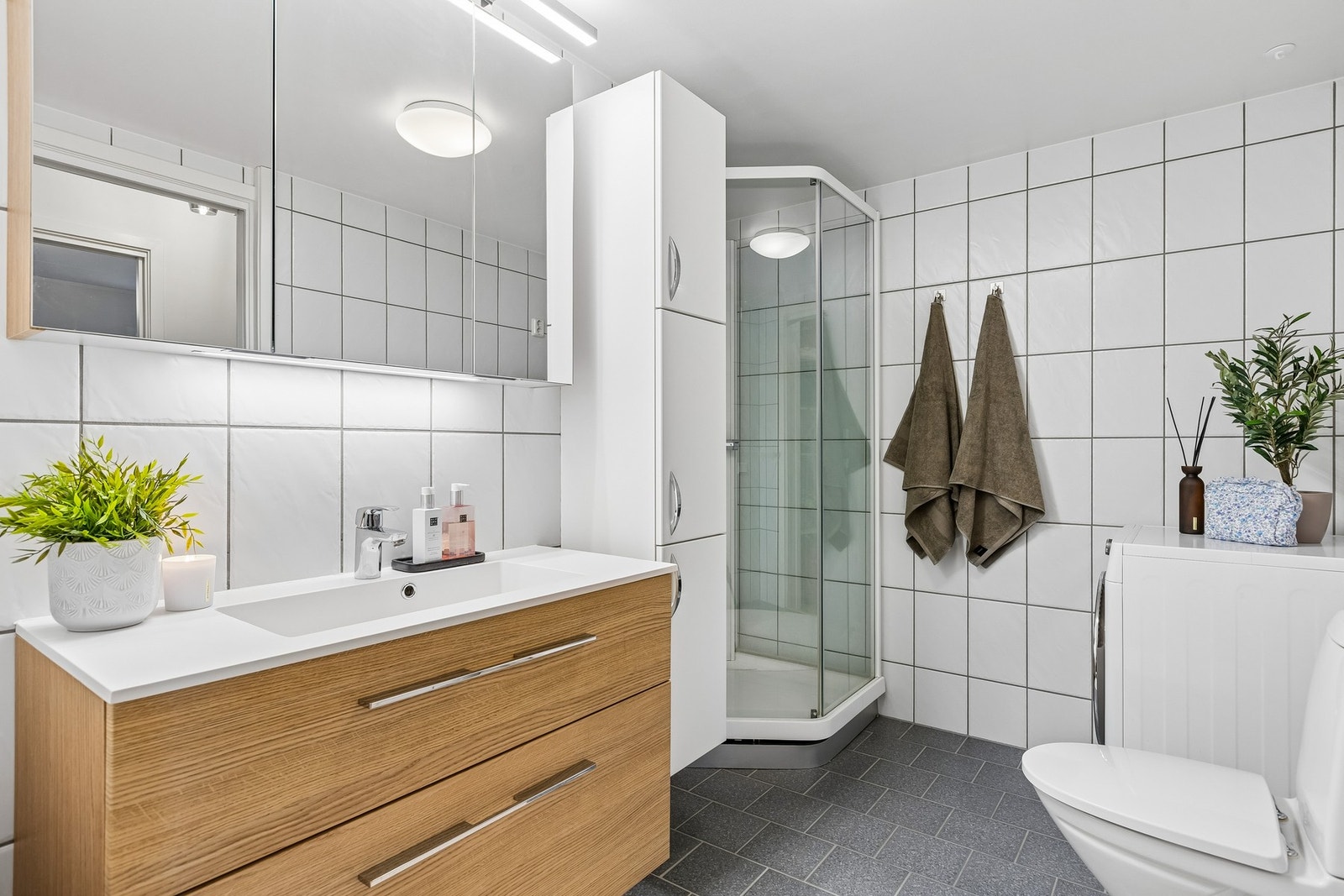 Bad innredet med stor servant og skap, dusjkabinett og opplegg for vaskemaskin. Galleribilde