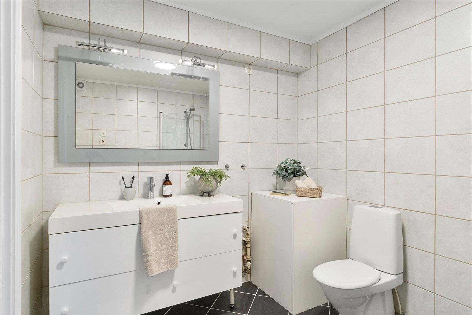 Badet fremstår som arealeffektivt med baderomsinnredning i hvit utførelse. Opplegg for vaskemaskin og tørketrommel kan også nevnes. Galleribilde