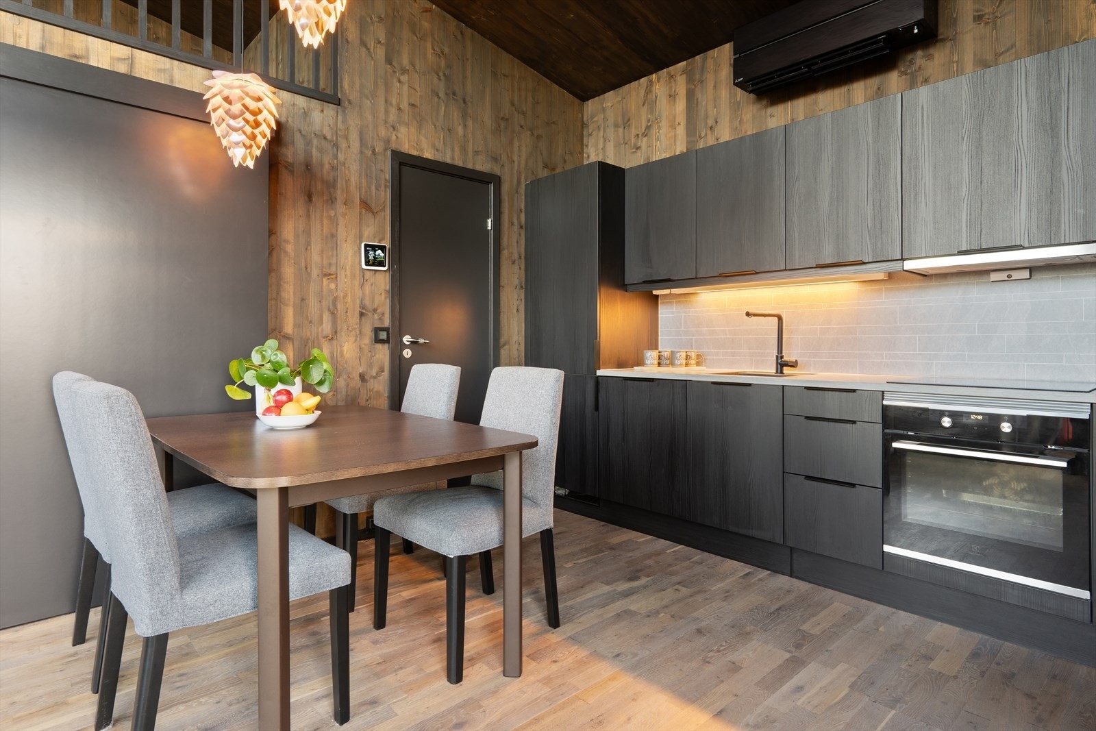 Sort, slett kjøkkeninnredning med laminert benkeplate. Det er integrert kombinert vaskemaskin/tørketrommel i innredningen. Galleribilde