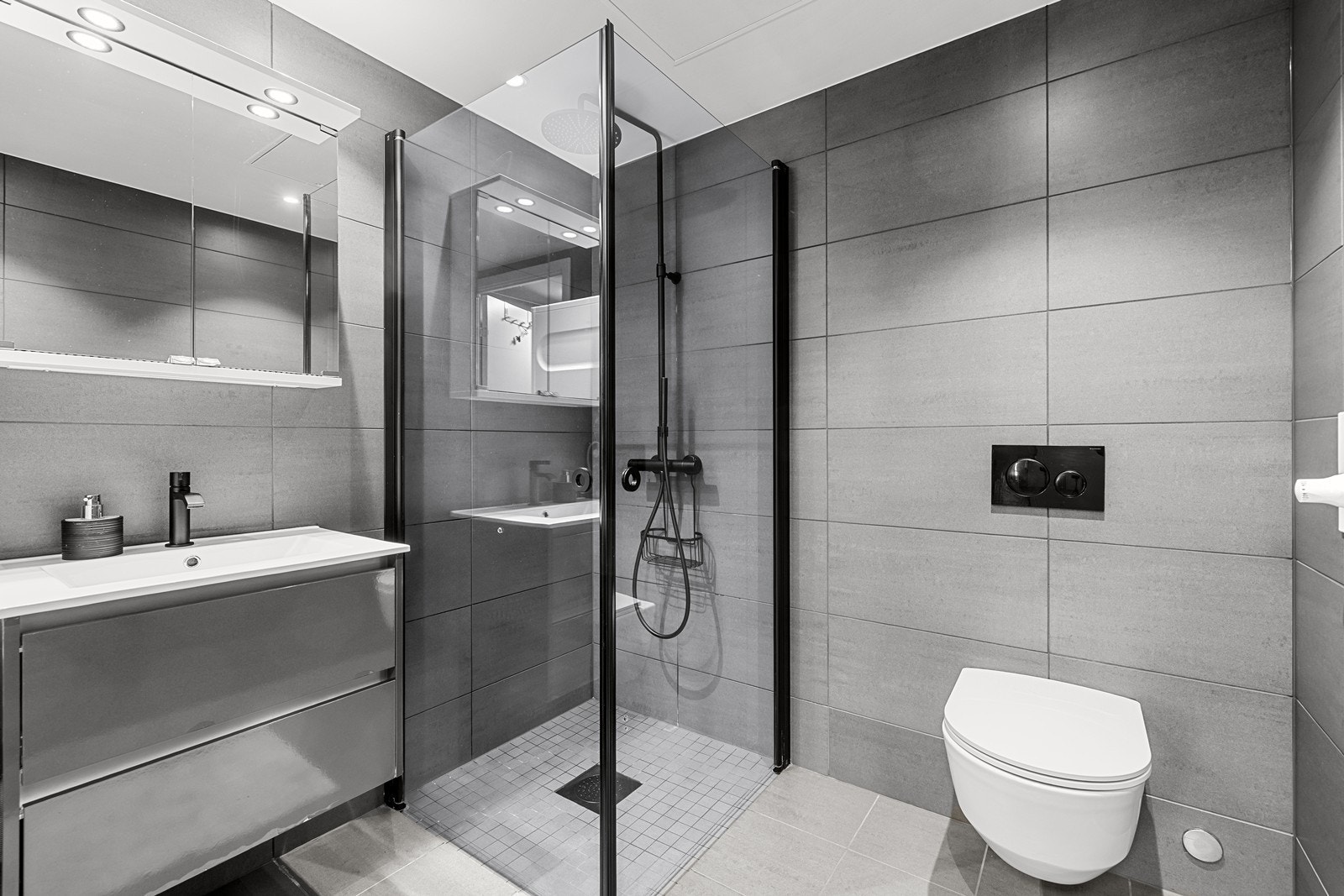 Badet er utstyrt med vegghengt toalett med innebygget sisterne og et dusjhjørne med stilrene glassvegger. Galleribilde