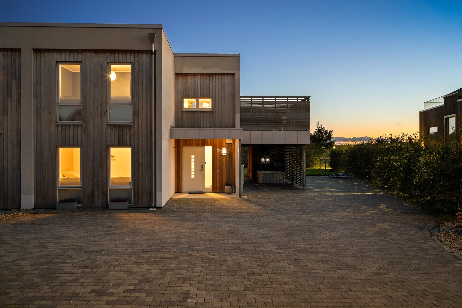 Eiendommen har en stor, steinbelagt gårdsplass med carport, sportsbod og to elbilladere. Galleribilde