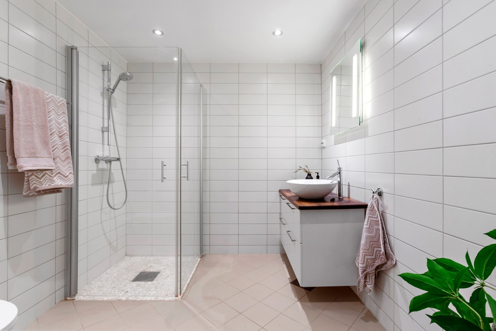 Flislagt bad med gulvvarme, dusjhjørne med innfellbare glassdører og downlights i taket. Galleribilde