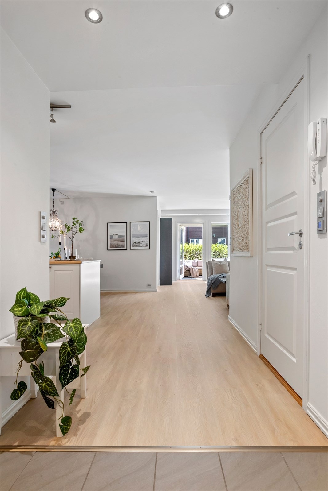 Fra entreen åpner leiligheten seg opp mot stuen og uteplassen, noe som skaper en lys og innbydende ankomst. Galleribilde