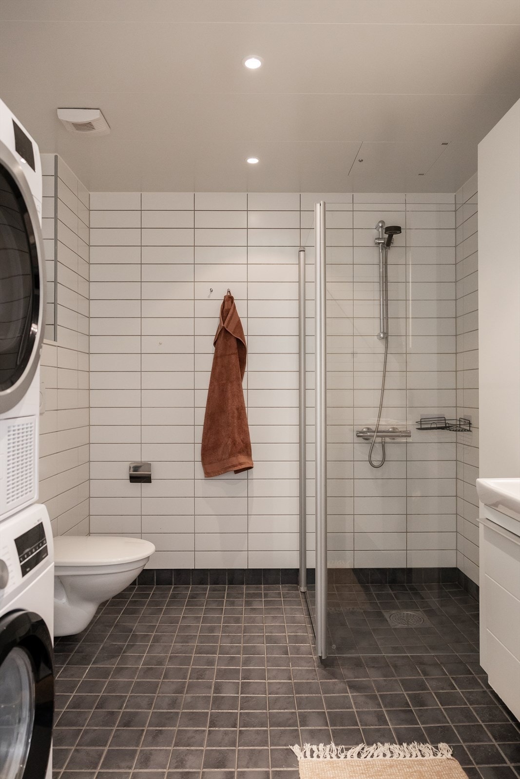 Badet er innredet med dusjhjørne med herdet glassdører, servant med skuffeinnredning og vegghengt toalett. Galleribilde