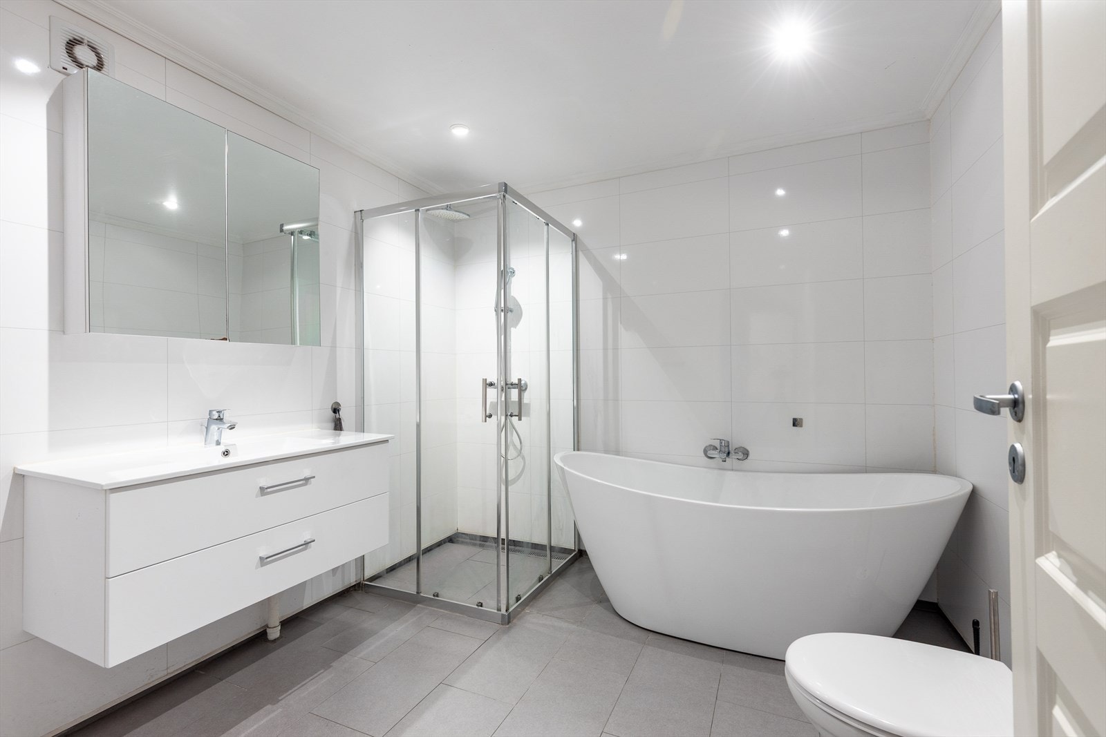 Badet har flislagt gulv med elektriske varmekabler, vegghengt toalett og badekar. Galleribilde
