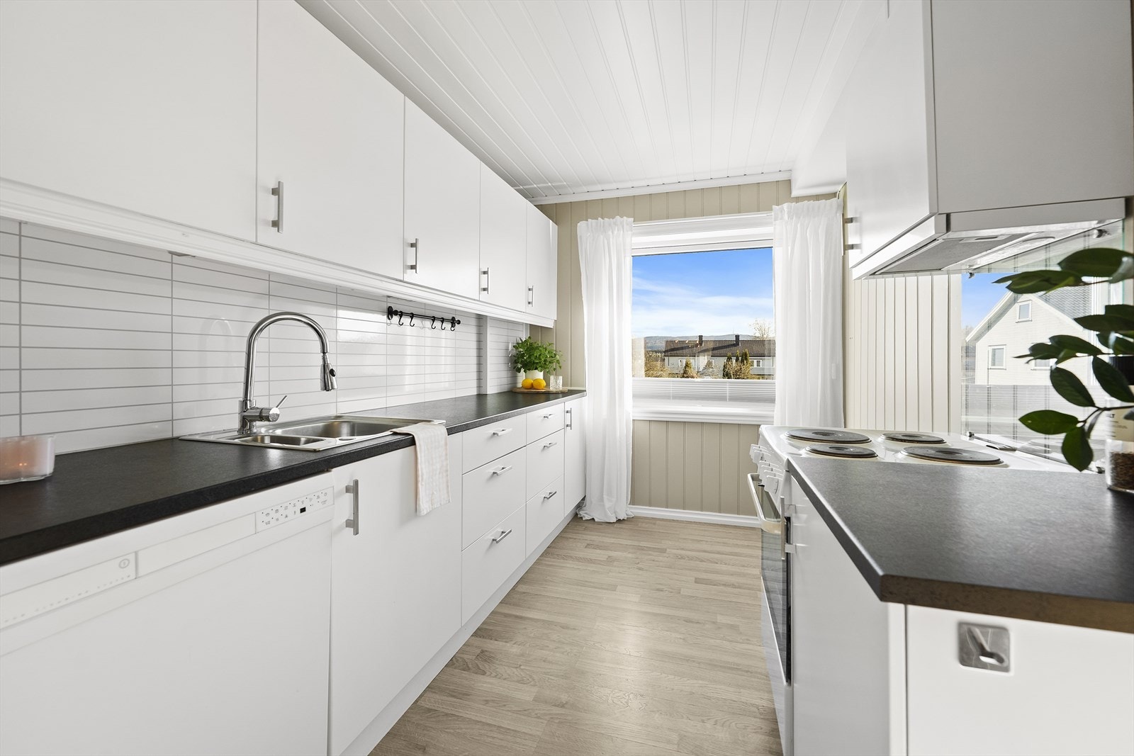 Kjøkkenet er et eget rom med en praktisk innredning med hvite, glatte fronter og laminert benkeplate. Galleribilde