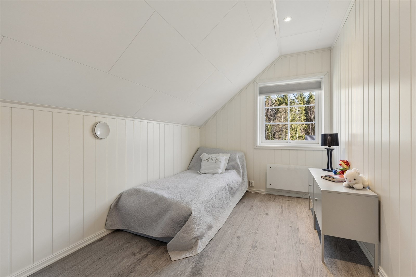 Det andre soverommet i loftsetasjen er lyst og trivelig, med panelplater på veggene. Galleribilde