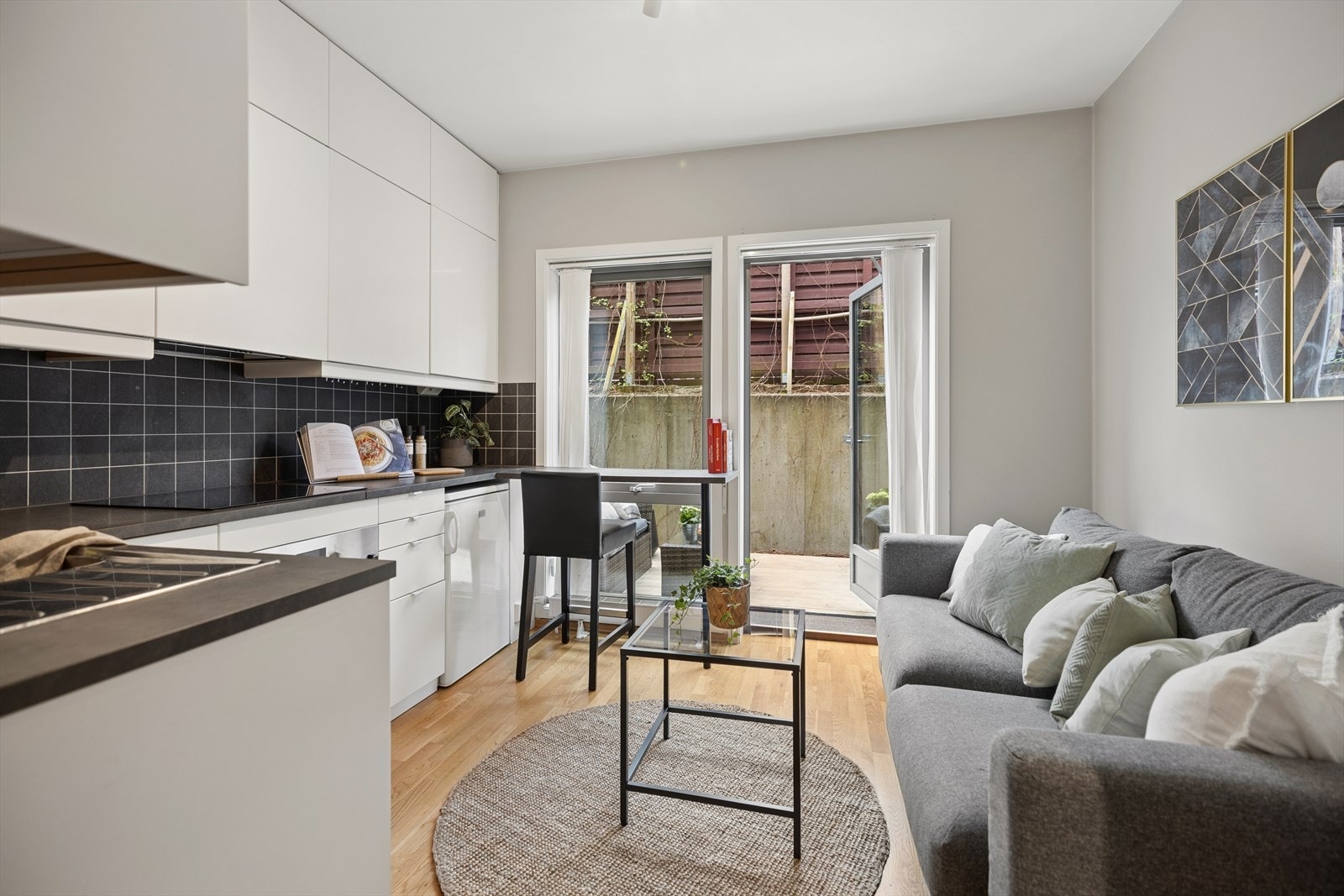 Den åpne kjøkken/stue-løsningen er hyggelig og innbydende med plass til sofa og spiseplass i barløsning. Galleribilde