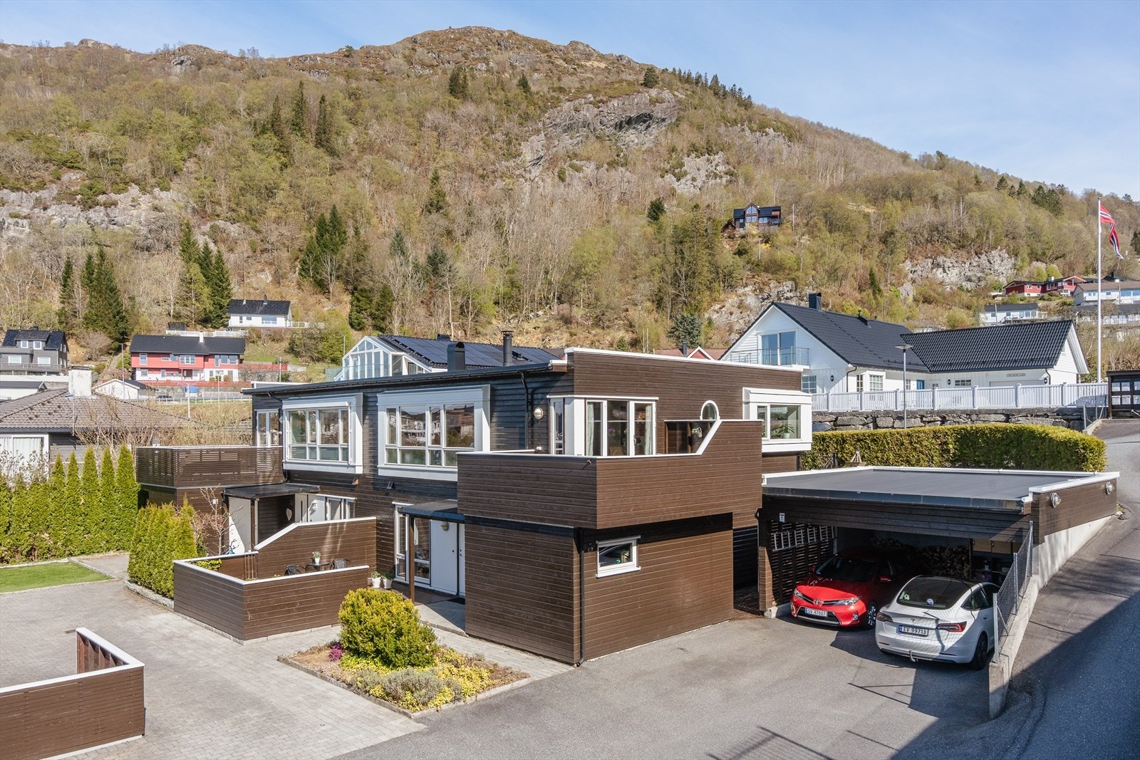 Eiendommen har en pent opparbeidet tomt med asfaltert tilkomst og biloppstillingsplasser. Boligen disponerer halve carporten. Den siden som vender mot huset. Galleribilde