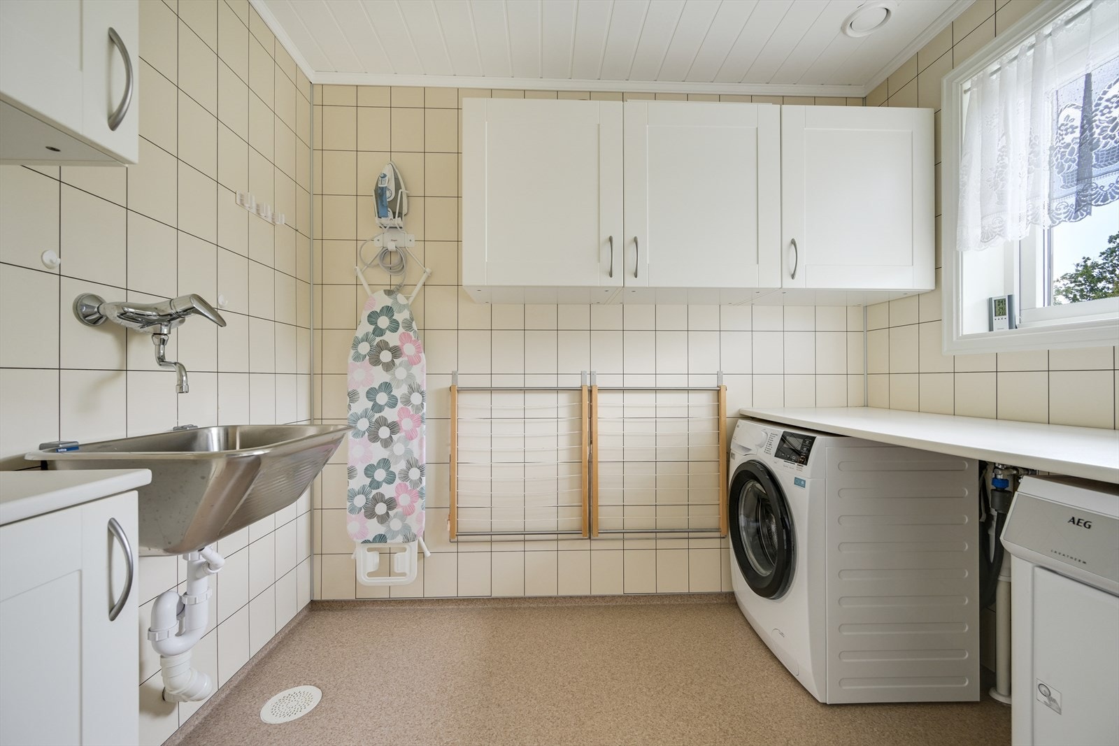 Separat vaskerom med vinylbelegg med gulvvarme, skyllekar og opplegg for vaskemaskin. Galleribilde