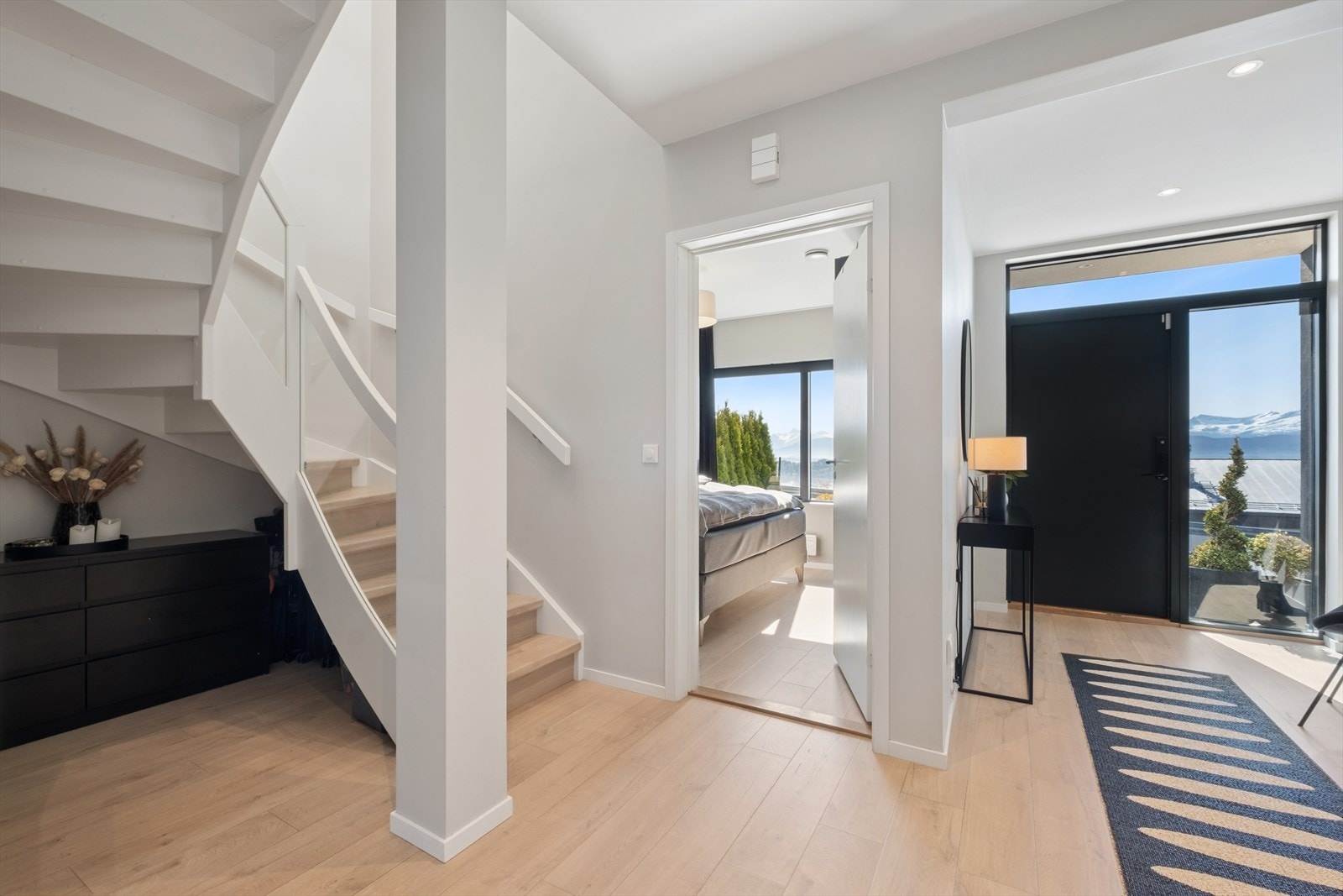 Romslig entré med varme i gulvet og en malt tretrapp som leder opp til andre etasje. Galleribilde