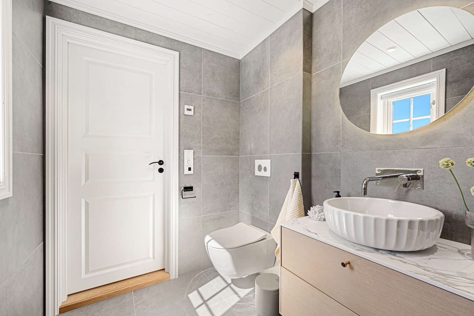 Dette badet fremstår ekstra påkostet med innbyggingsarmatur både i dusjhjørne og ved servant. Rommet inneholder servant med skuffeinnredning, dusjhjørne og vegghengt toalett. Galleribilde