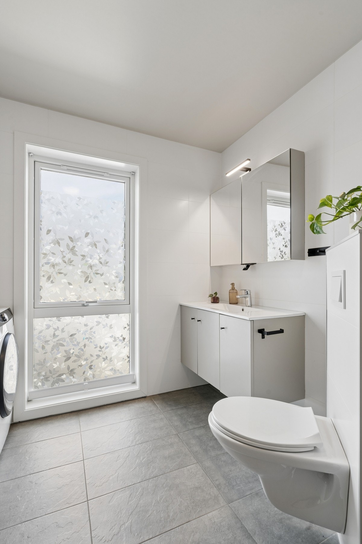 Badet er innredet med veggmontert toalett og servantinnredning. Galleribilde
