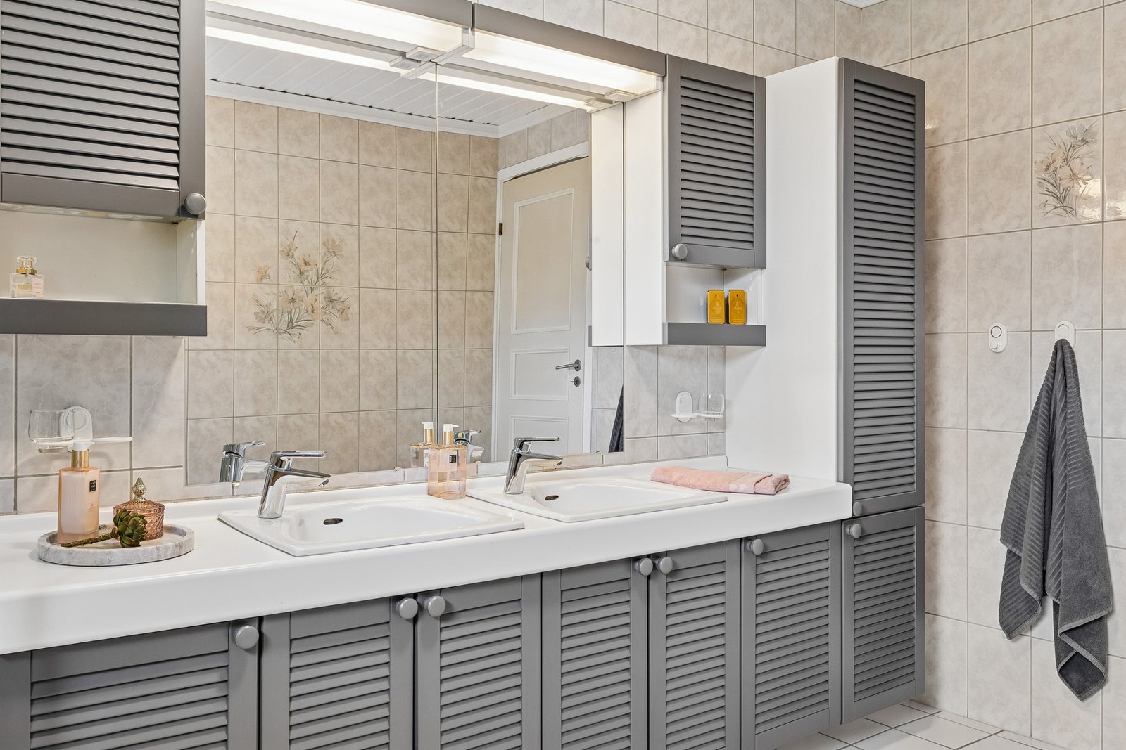 Badet er innredet med vegghengt servantinnredning, speil med overlys, dusjkabinett og badekar. Galleribilde