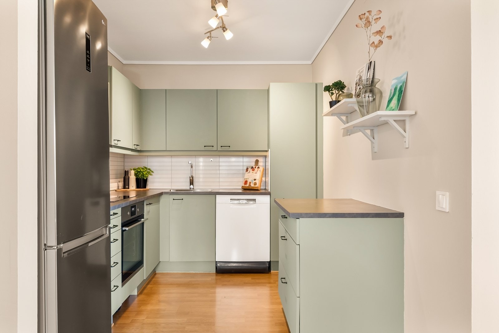 Innredningen har glatte fronter som er malt av eier, noe som gir kjøkkenet et moderne, stilrent og personlig uttrykk. Den slitesterke laminatbenkeplaten er både praktisk og enkel å vedlikeholde, og gir godt med plass til matlaging og forberedelser. Galleribilde
